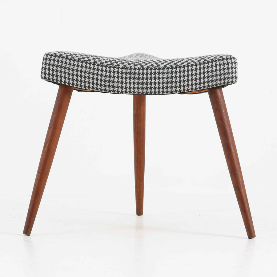 デンマーク製スツールです。3本脚の軽やかなフォルムに、チーク材の温もりが感じられる北欧ビンテージらしい佇まいが魅力です。三角形の座面は座り心地を考慮した絶妙な曲面で構成され、張地は千鳥格子柄のファブリックで仕上げました。玄関や寝室の補助椅子としてはもちろん、オットマンとしても活躍します。経年により深みを増したチーク材の脚が空間に上品な印象を与える一脚です。