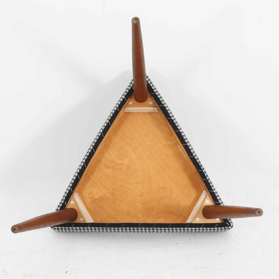 デンマーク製スツールです。3本脚の軽やかなフォルムに、チーク材の温もりが感じられる北欧ビンテージらしい佇まいが魅力です。三角形の座面は座り心地を考慮した絶妙な曲面で構成され、張地は千鳥格子柄のファブリックで仕上げました。玄関や寝室の補助椅子としてはもちろん、オットマンとしても活躍します。経年により深みを増したチーク材の脚が空間に上品な印象を与える一脚です。