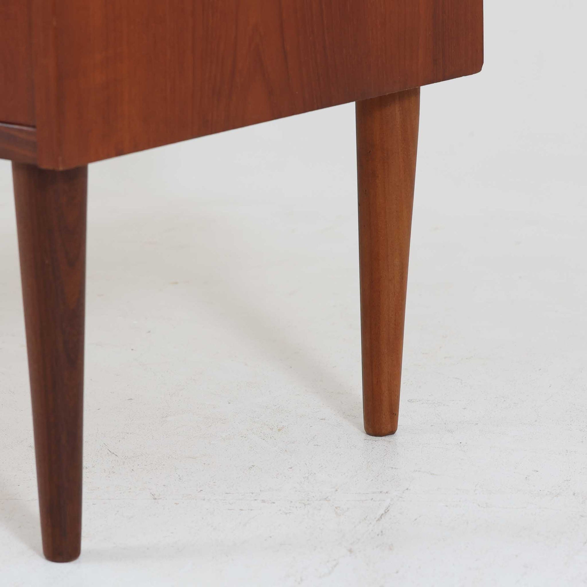 デンマーク製ライティングビューロです。上段には小引き出しと仕切り棚、中央には小さなミラーが備わり、書き物や身支度など多用途にお使いいただけます。チーク材の深みある色合いと滑らかな木目が美しく、シンプルで直線的なフォルムが落ち着いた印象を与えます。引き出しの斜めに削り出された取っ手やテーパー脚など、北欧らしい洗練されたディテールが魅力です。経年により増した艶が味わい深く、リビングや寝室に上品な温もりを添える一台です。