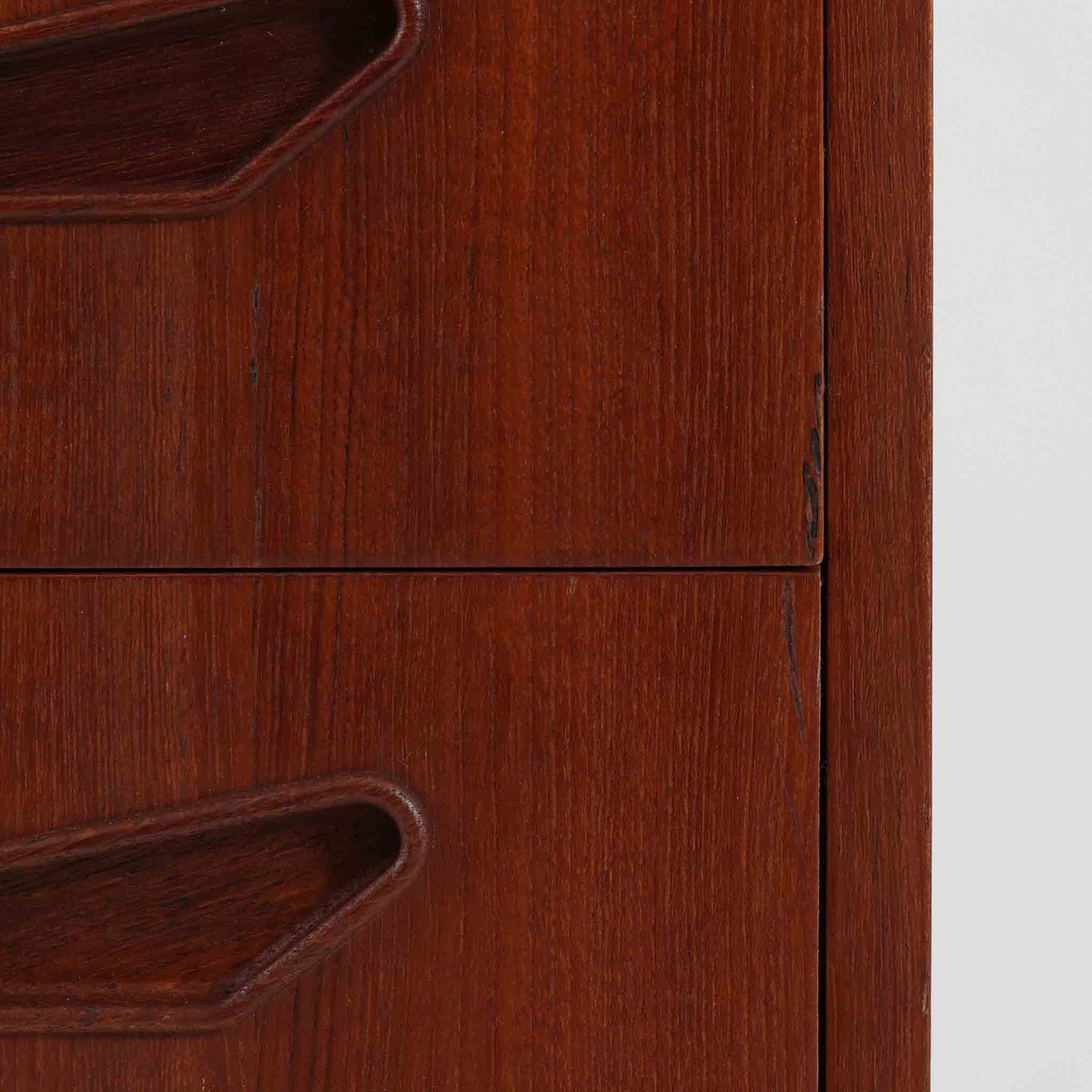 デンマーク製ライティングビューロです。上段には小引き出しと仕切り棚、中央には小さなミラーが備わり、書き物や身支度など多用途にお使いいただけます。チーク材の深みある色合いと滑らかな木目が美しく、シンプルで直線的なフォルムが落ち着いた印象を与えます。引き出しの斜めに削り出された取っ手やテーパー脚など、北欧らしい洗練されたディテールが魅力です。経年により増した艶が味わい深く、リビングや寝室に上品な温もりを添える一台です。