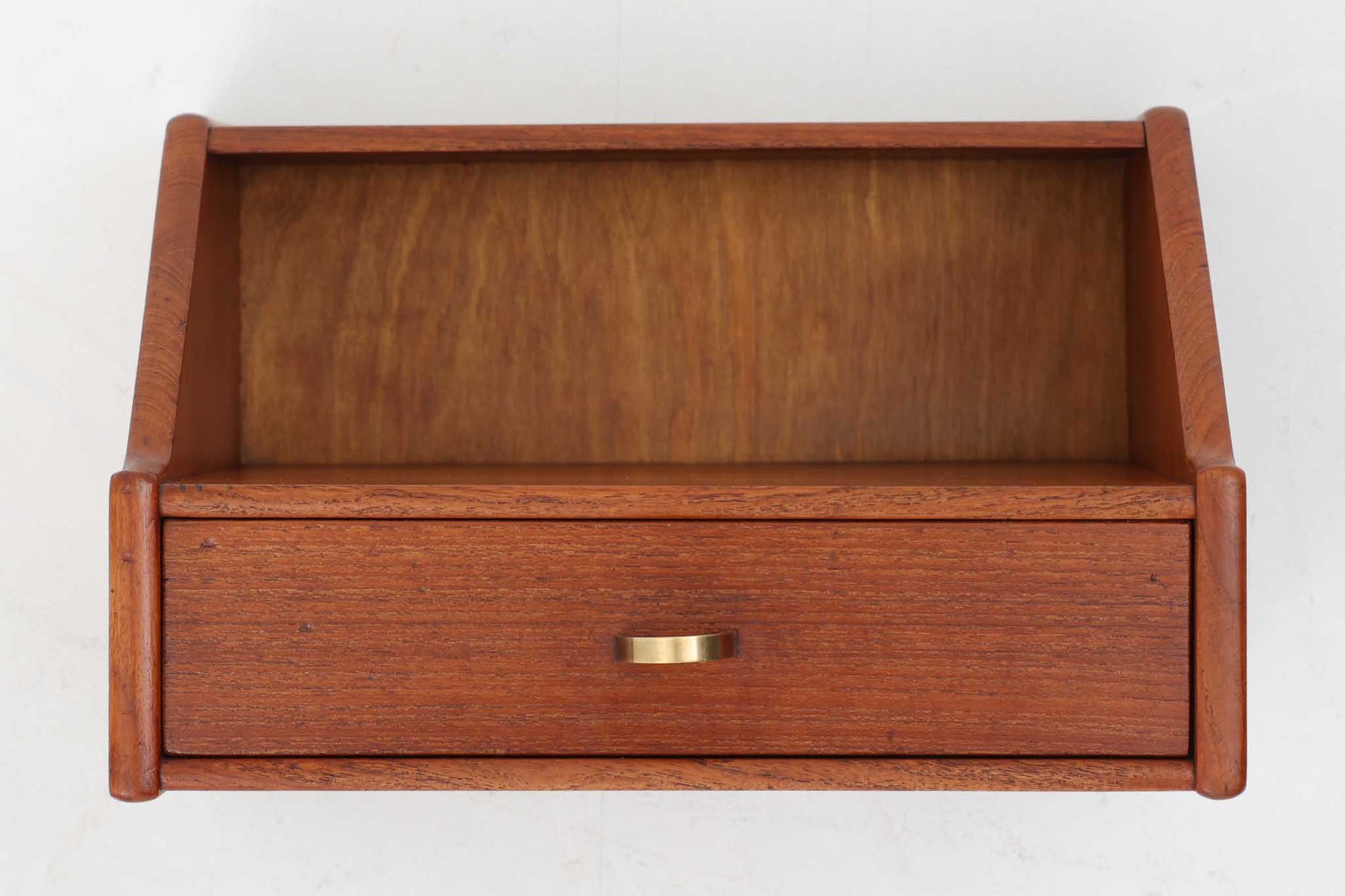 北欧より買い付けたウォールシェルフ。良質なチーク材が贅沢に使用され、経年変化によって深みを増した色味が魅力です。引き出しの小さなゴールド色の取手がデザインのアクセントとなっています。引き出し1段、天板と引き出しの間には物を置けるスペースもあり、リビングや寝室、オフィスの壁面収納にぴったり。飾り棚としても、小物の整理にも活躍します。