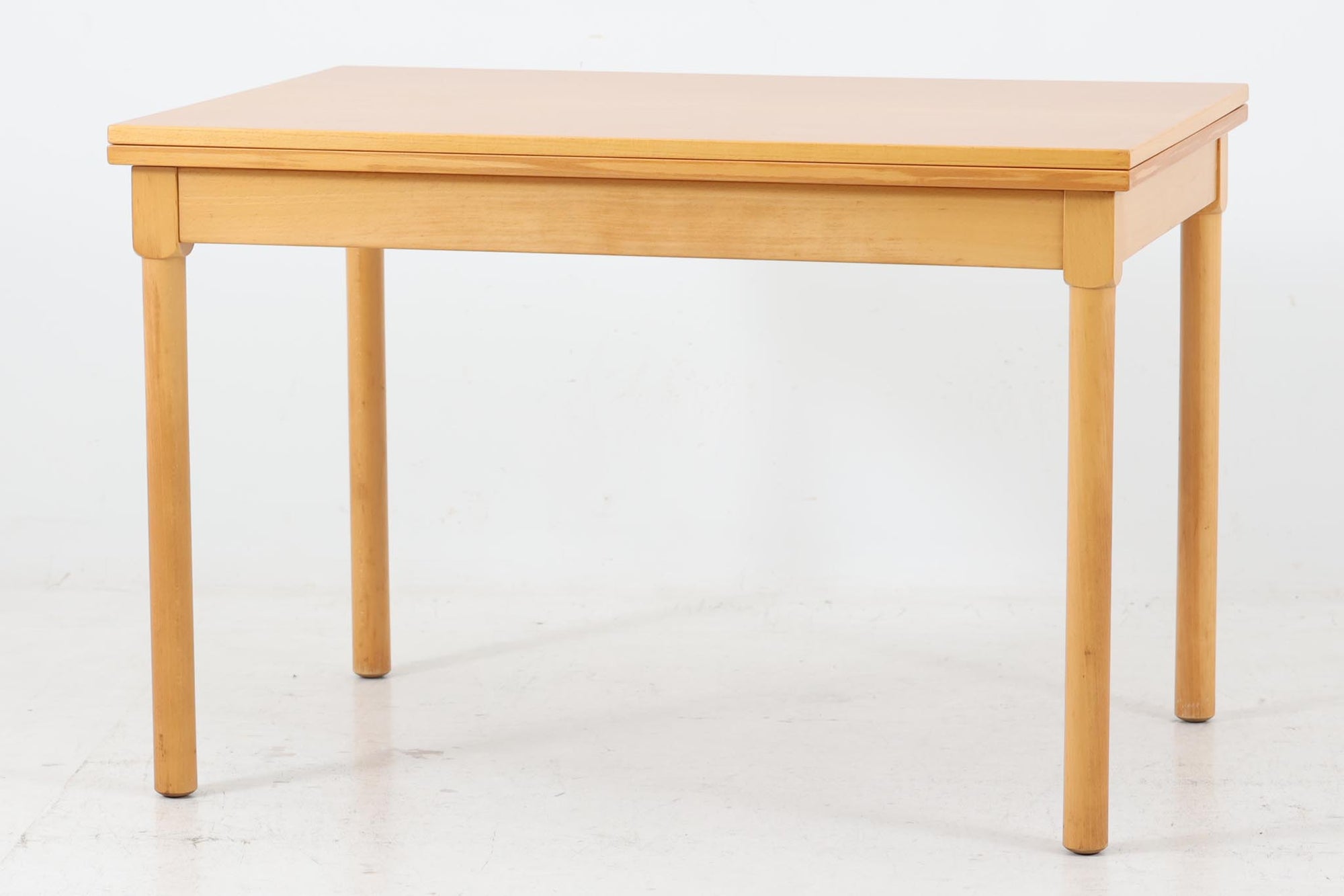 デンマークを代表するデザイナー、ボーエ・モーエンセン（Børge mogensen） による拡張式センターテーブル。1976年にFritz Hansen（フリッツ・ハンセン）社によって製造された、北欧ヴィンテージ家具の逸品です。無駄を省いたシンプルなデザインながらも、堅牢な構造と機能性を兼ね備えており、モーエンセンらしい実用的な美しさが際立ちます。中央のヒンジを開くことで、天板を拡張することが可能。必要に応じて広げられるため、普段使いから来客時まで幅広く活躍します。素材には上質なビーチ材が使用され、温かみのあるナチュラルな風合いが魅力的です。