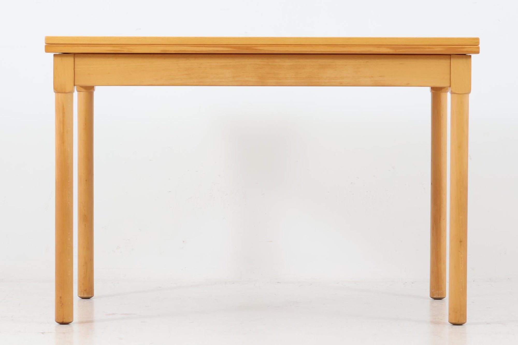 デンマークを代表するデザイナー、ボーエ・モーエンセン（Børge mogensen） による拡張式センターテーブル。1976年にFritz Hansen（フリッツ・ハンセン）社によって製造された、北欧ヴィンテージ家具の逸品です。無駄を省いたシンプルなデザインながらも、堅牢な構造と機能性を兼ね備えており、モーエンセンらしい実用的な美しさが際立ちます。中央のヒンジを開くことで、天板を拡張することが可能。必要に応じて広げられるため、普段使いから来客時まで幅広く活躍します。素材には上質なビーチ材が使用され、温かみのあるナチュラルな風合いが魅力的です。