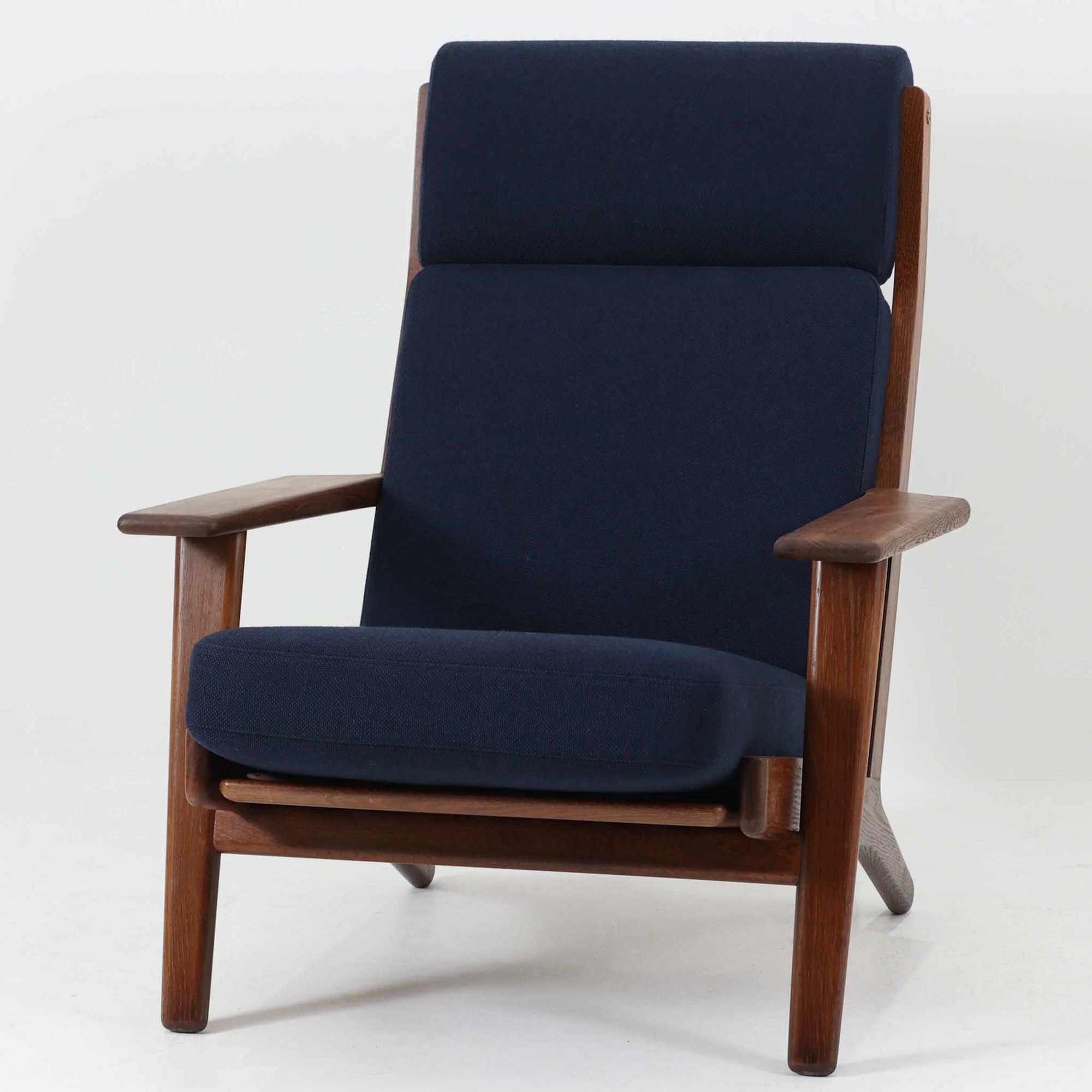 Hans J. Wegnerがデザインし、Getamaが製作したGE290Aハイバックシングルソファです。ダークオーク材の堅牢なフレームは丸みを帯びたアームと後方へ傾斜した脚部が特徴で、身体をやさしく受け止める構造美が際立ちます。張り替えられた落ち着いた色調のクッションは、内部にビンテージ特有のスプリングを内包し、程よい弾力と快適な座り心地を実現。読書や寛ぎの時間に最適で、経年により深みを増した木部の質感が北欧ビンテージならではの存在感と上質な雰囲気を空間に添える一脚です。