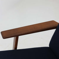 Hans J. Wegnerがデザインし、Getamaが製作したGE290Aハイバックシングルソファです。ダークオーク材の堅牢なフレームは丸みを帯びたアームと後方へ傾斜した脚部が特徴で、身体をやさしく受け止める構造美が際立ちます。張り替えられた落ち着いた色調のクッションは、内部にビンテージ特有のスプリングを内包し、程よい弾力と快適な座り心地を実現。読書や寛ぎの時間に最適で、経年により深みを増した木部の質感が北欧ビンテージならではの存在感と上質な雰囲気を空間に添える一脚です。