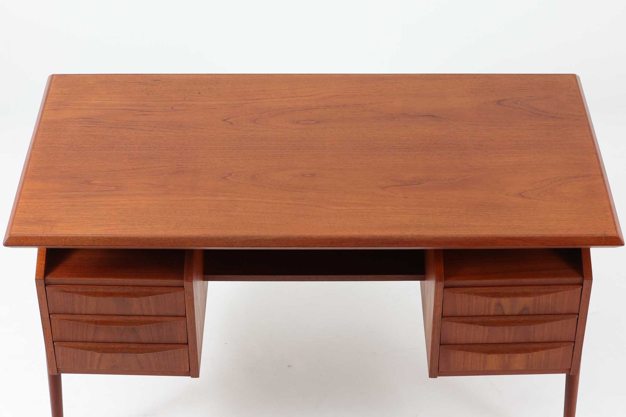 この両袖デスクは、左右に取り付けられた、下に向かって斜めに開いた脚が特徴であり、天板が浮いたような独特なデザインです。全面に上質なチーク材が用いられ、背面には収納スペースも備わっており、使い勝手と美しさを兼ね備えた一台となっています。天板に5mmほどの反りがございますので、それを考慮した価格に設定しております。