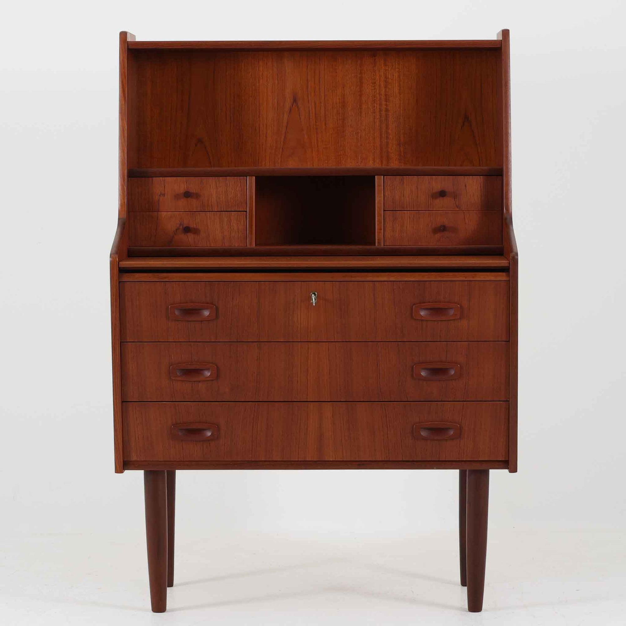 Egon Jensenによるデザイン、Hanbjerg Mobelfabrik製のこちらのライティングビューロは、上段に小引き出しとオープン収納、中央には開閉式の鏡を備えた機能的な構成が魅力です。素材にはチーク材が用いられ、美しい木目と落ち着いた色調が上質な空間を演出します。天板を引き出せばドレッサーやワークスペースとしても活用可能で、コンパクトながら多用途に対応できる点が特徴です。デンマーク製ならではの丁寧な造りと、経年により深まった風合いがビンテージ家具の味わいを感じさせます。