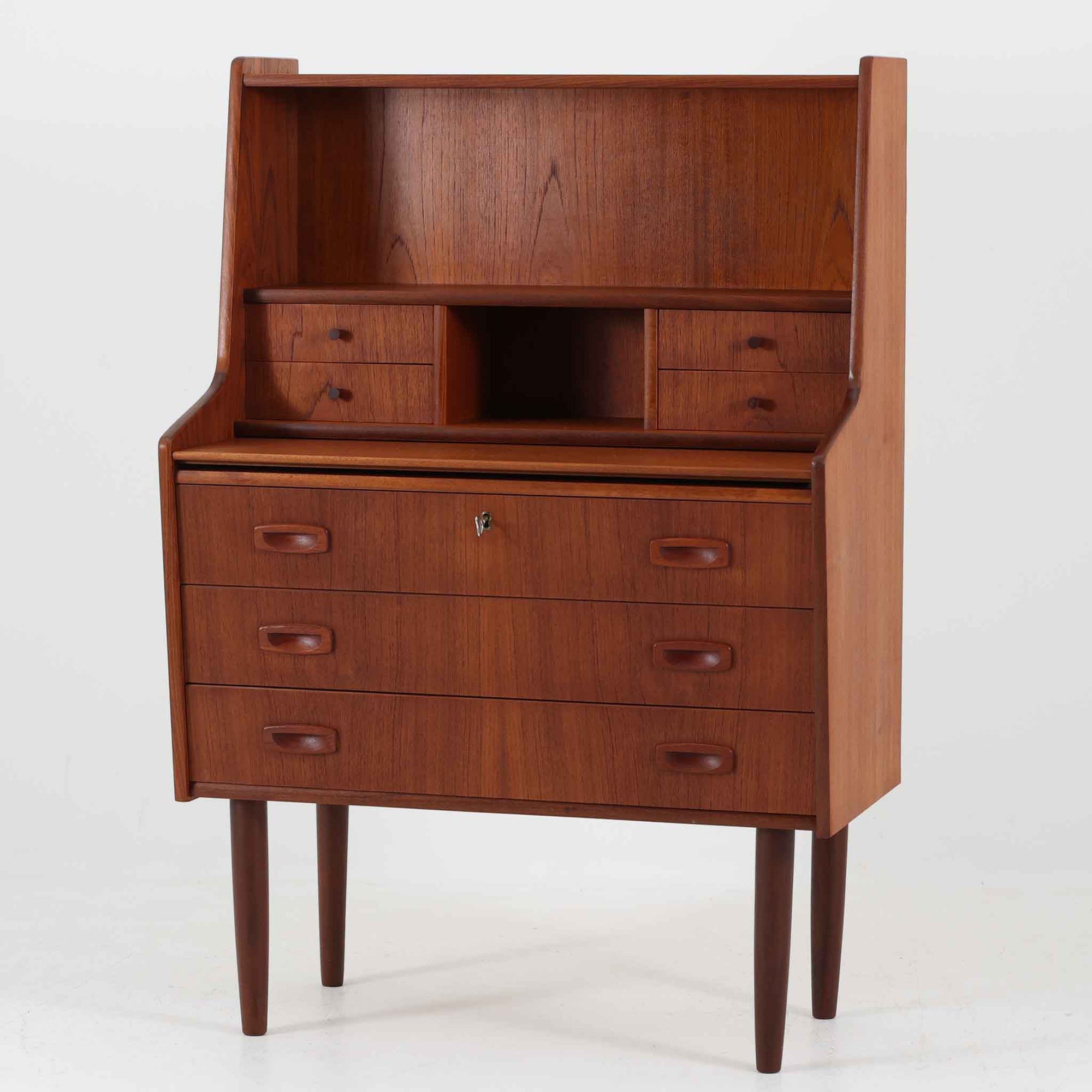 Egon Jensenによるデザイン、Hanbjerg Mobelfabrik製のこちらのライティングビューロは、上段に小引き出しとオープン収納、中央には開閉式の鏡を備えた機能的な構成が魅力です。素材にはチーク材が用いられ、美しい木目と落ち着いた色調が上質な空間を演出します。天板を引き出せばドレッサーやワークスペースとしても活用可能で、コンパクトながら多用途に対応できる点が特徴です。デンマーク製ならではの丁寧な造りと、経年により深まった風合いがビンテージ家具の味わいを感じさせます。