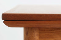 デンマークの名工Slagelse Mobelvaerk社が手掛けたこちらのダイニングテーブルは、アーチ状の幕板が特徴であり、異なる素材の組み合わせが美しさを際立たせます。天板には上質なチーク材が用いられ、脚部にはナチュラルなオーク材が採用されています。また、幕板は強度と使い勝手が考慮され、通常時には4人、拡張時には6～8人が快適に使用できる設計となっています。
