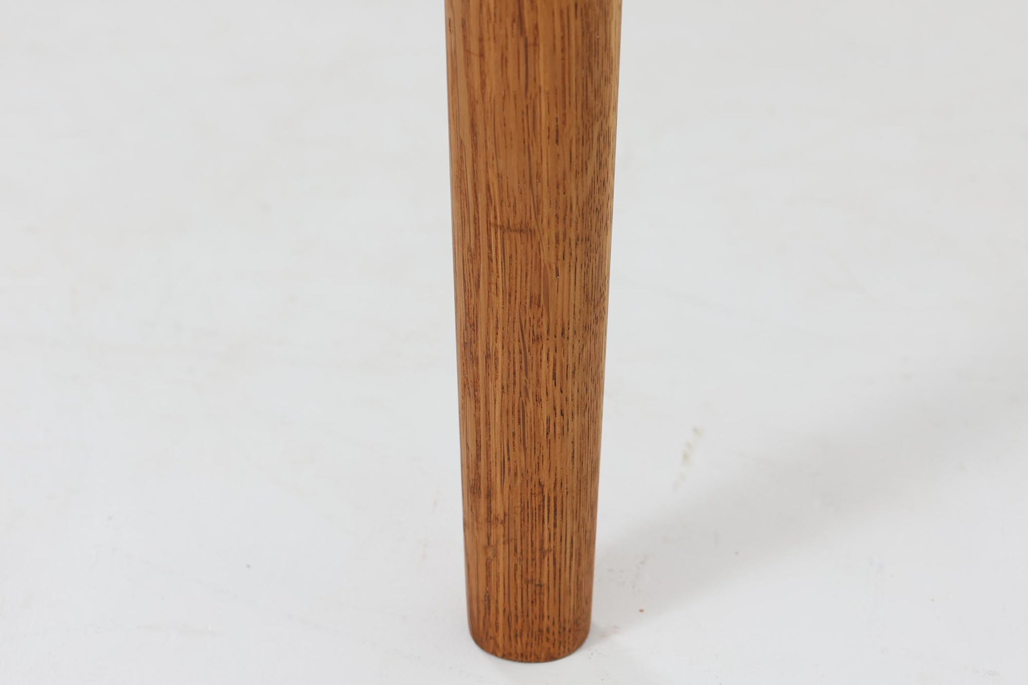 デンマークの名工Slagelse mobelvaerk社が手掛けたこちらのダイニングテーブルは、アーチ状の幕板が特徴であり、異なる素材の組み合わせが美しさを際立たせます。天板には上質なチーク材が用いられ、脚部にはナチュラルなオーク材が採用されています。また、幕板は強度と使い勝手が考慮され、通常時には4人、拡張時には6～8人が快適に使用できる設計となっています。