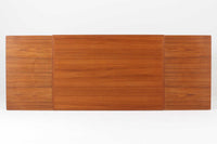 デンマークの名工Slagelse Mobelvaerk社が手掛けたこちらのダイニングテーブルは、アーチ状の幕板が特徴であり、異なる素材の組み合わせが美しさを際立たせます。天板には上質なチーク材が用いられ、脚部にはナチュラルなオーク材が採用されています。また、幕板は強度と使い勝手が考慮され、通常時には4人、拡張時には6～8人が快適に使用できる設計となっています。