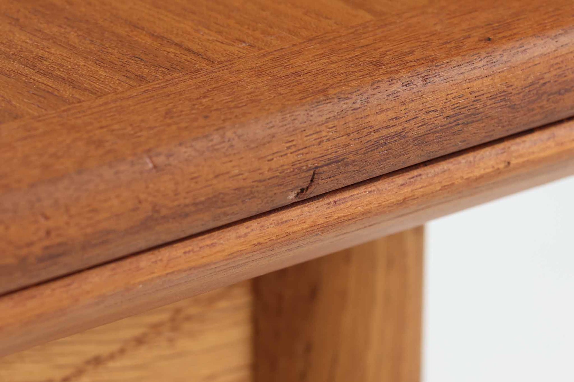 デンマークの名工Slagelse mobelvaerk社が手掛けたこちらのダイニングテーブルは、アーチ状の幕板が特徴であり、異なる素材の組み合わせが美しさを際立たせます。天板には上質なチーク材が用いられ、脚部にはナチュラルなオーク材が採用されています。また、幕板は強度と使い勝手が考慮され、通常時には4人、拡張時には6～8人が快適に使用できる設計となっています。