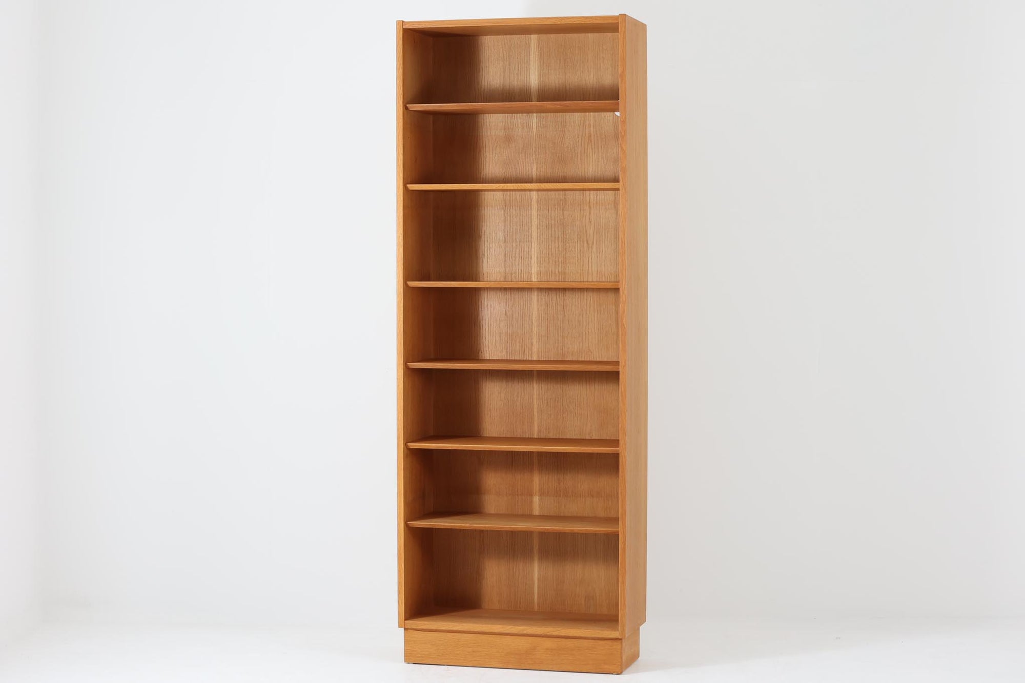 Hundevad & Co社製の造りが良いブックシェルフです。良質なオーク材が使用されています。大型で様々な本が収納可能です。Poul Hundevadならではの棚板前面のスリットとタボが見えない設計により非常にすっきりとした印象に仕上がっています。通常は台輪が側面とフラットなのですが、こちらのシェルフは台輪が少し内側に入っています。デンマーク購入時よりこの仕様ですので、予めご了承くださいませ。