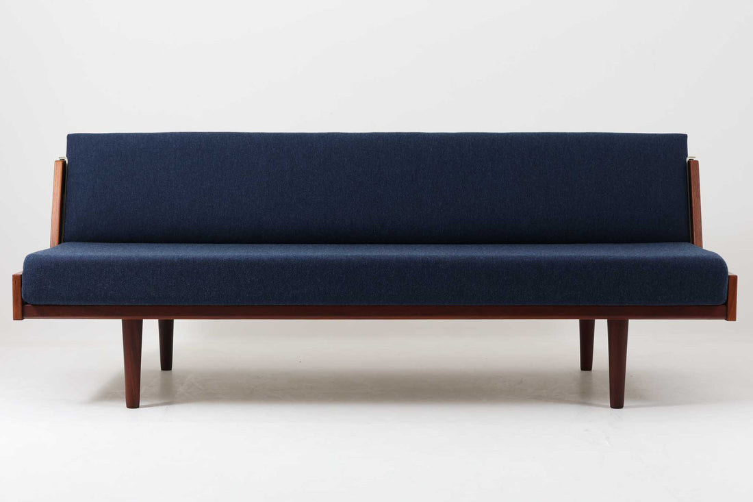 デンマークの名門家具メーカーGetama（ゲタマ）より、Hans J. Wegner（ハンス・J・ウェグナー）によってデザインされたビンテージのデイベッド「GE258」のご紹介です。チーク材のフレームに、希少な丸脚仕様が特徴的なモデルで、無駄のない美しい直線と有機的なフォルムが融合した北欧モダンデザインの代表作です。背もたれを後方に倒すことでベッドとしてもご使用いただける実用性の高い構造で、張地は落ち着いたネイビー系のファブリックで張り替え済みです。チーク材の木目が美しく、経年による味わいも感じられる逸品です。