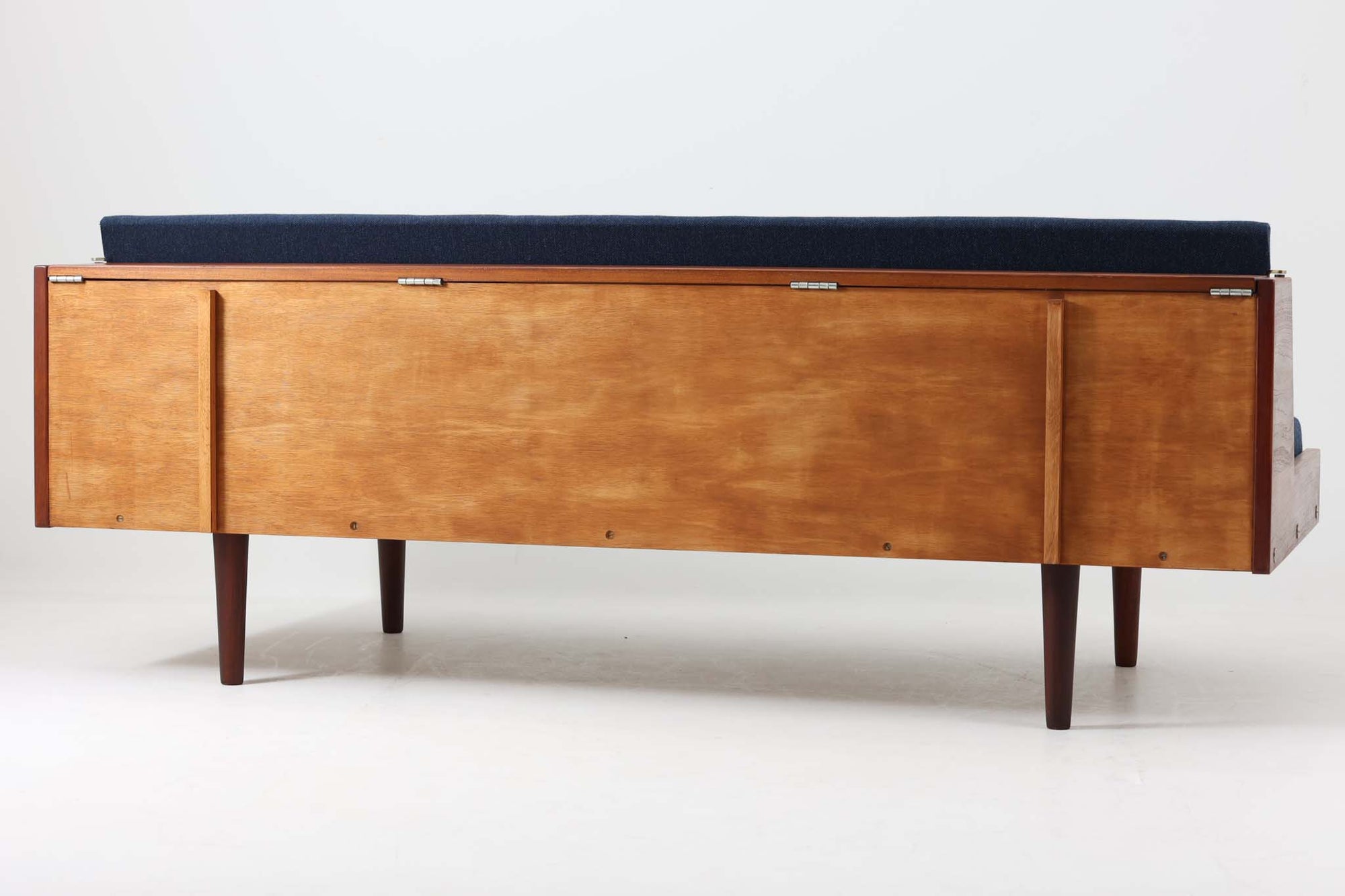 デンマークの名門家具メーカーGetama（ゲタマ）より、Hans J. Wegner（ハンス・J・ウェグナー）によってデザインされたビンテージのデイベッド「GE258」のご紹介です。チーク材のフレームに、希少な丸脚仕様が特徴的なモデルで、無駄のない美しい直線と有機的なフォルムが融合した北欧モダンデザインの代表作です。背もたれを後方に倒すことでベッドとしてもご使用いただける実用性の高い構造で、張地は落ち着いたネイビー系のファブリックで張り替え済みです。チーク材の木目が美しく、経年による味わいも感じられる逸品です。