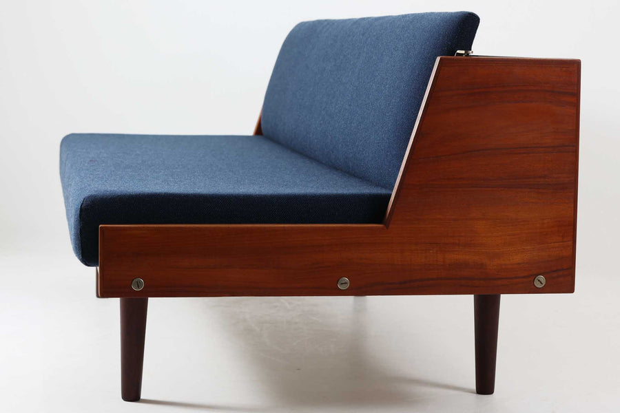 デンマークの名門家具メーカーGetama（ゲタマ）より、Hans J. Wegner（ハンス・J・ウェグナー）によってデザインされたビンテージのデイベッド「GE258」のご紹介です。チーク材のフレームに、希少な丸脚仕様が特徴的なモデルで、無駄のない美しい直線と有機的なフォルムが融合した北欧モダンデザインの代表作です。背もたれを後方に倒すことでベッドとしてもご使用いただける実用性の高い構造で、張地は落ち着いたネイビー系のファブリックで張り替え済みです。チーク材の木目が美しく、経年による味わいも感じられる逸品です。