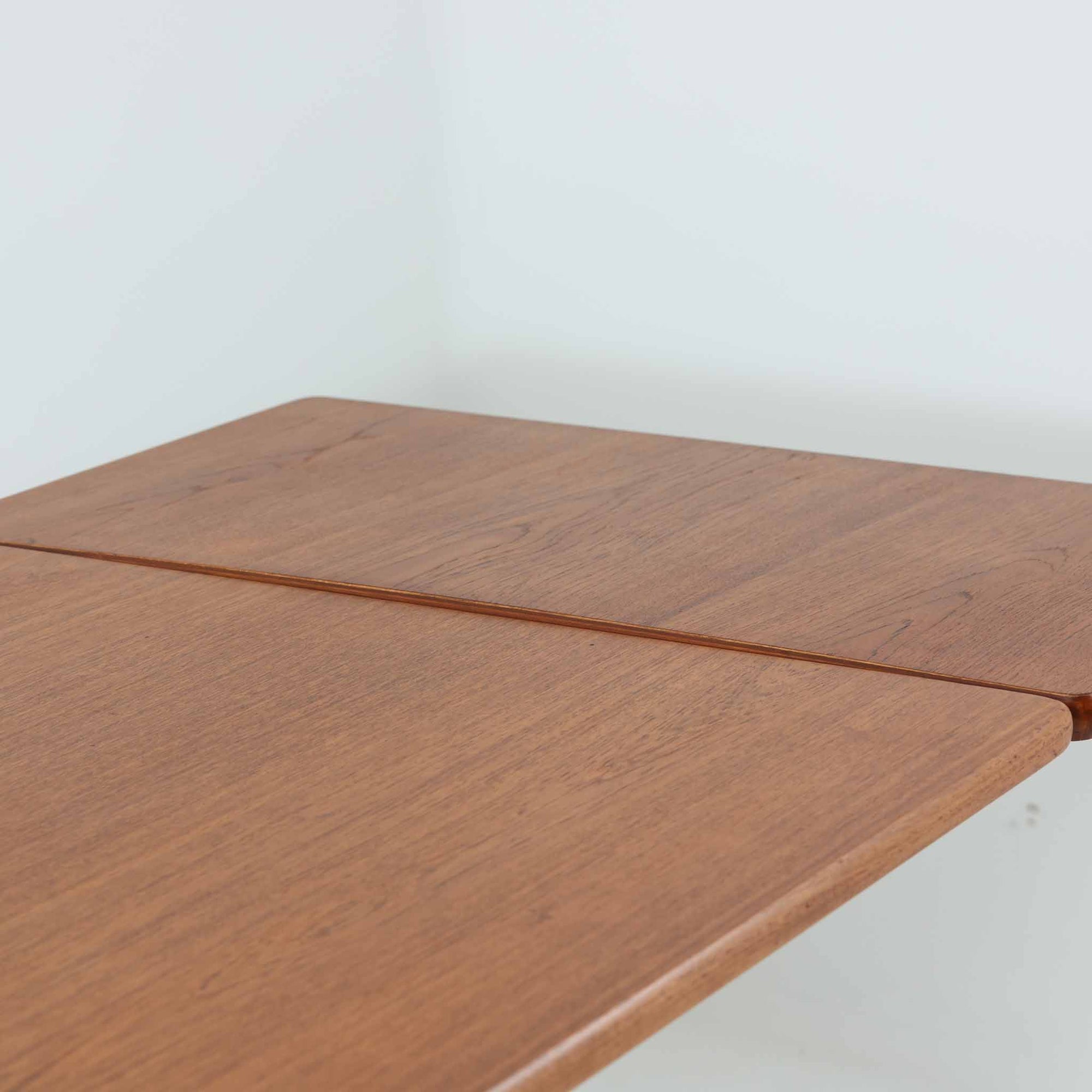 Borge Mogensen（ボーエ・モーエンセン）がFDB Moblerのために手掛けたC18ダイニングテーブルは、チーク材天板とオーク材脚部を組み合わせた北欧モダンを象徴するビンテージ家具で、直線的で端正なプロポーションと安定感のあるT字脚構造が特徴です。拡張板を備え、来客時や家族構成の変化にも柔軟に対応でき、日常使いから特別な食卓まで幅広く活躍します。現在はCarl Hansen &amp; Son社より復刻生産されていますが、チーク材天板とオーク材脚部という素材の組み合わせは当時のビンテージ品ならではの仕様で、脚部に用いられた真鍮製の留め具も現行品とは異なる形状となっています。経年により深みを増した木肌と、実用性を重視したモーエンセンらしい設計思想、そしてビンテージならではのディテールを味わえる一台です。