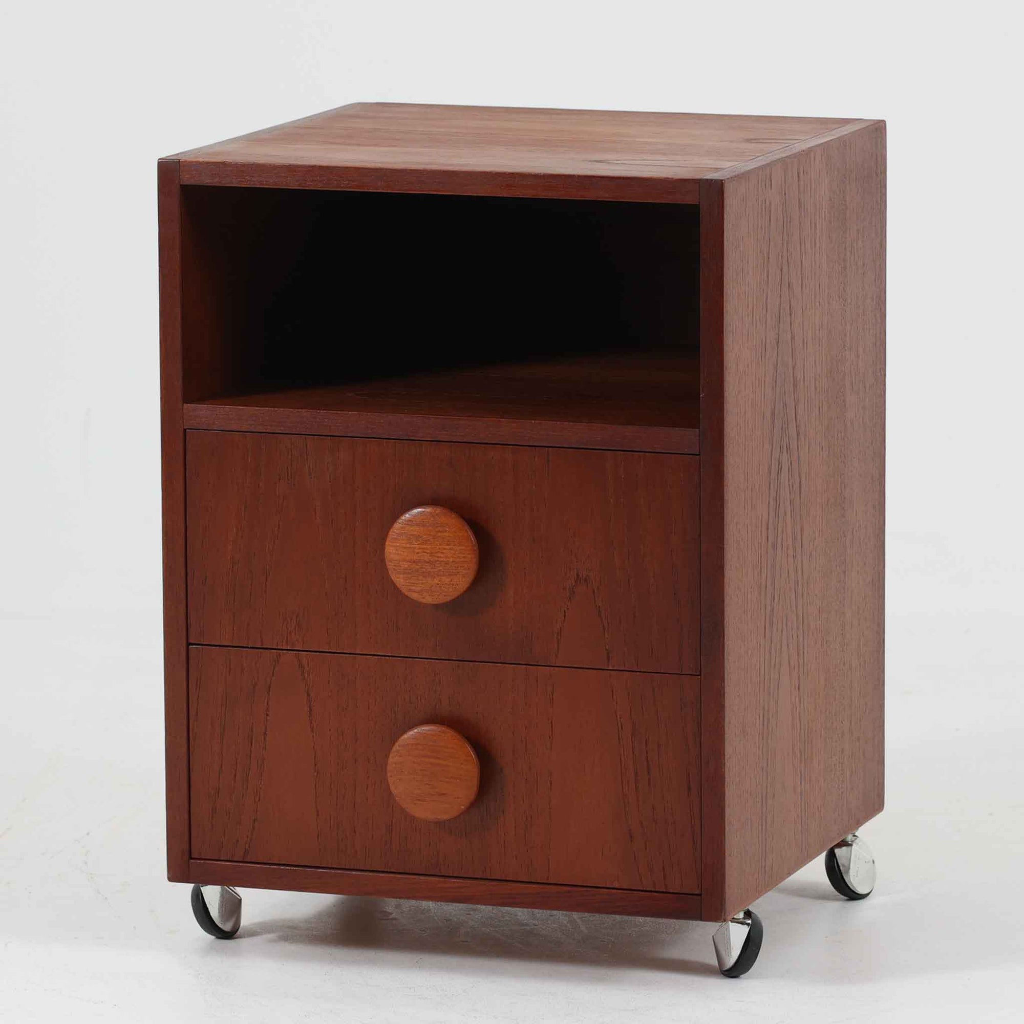 特徴的な丸型取手が目を引くこちらのサイドテーブルは、温かみのあるチーク材とシンプルな構造美が調和した北欧ビンテージ家具です。オープンスペースと2杯の引き出しに加え、英国製「ORBIT」キャスターを備え、滑らかな移動が可能です。幅40cmとコンパクトながらも機能性に優れており、ベッドサイドやソファ横の収納兼テーブルとして幅広く活躍します。実用性と遊び心を兼ね備えた一点物として、空間に心地よいアクセントを加えてくれます。