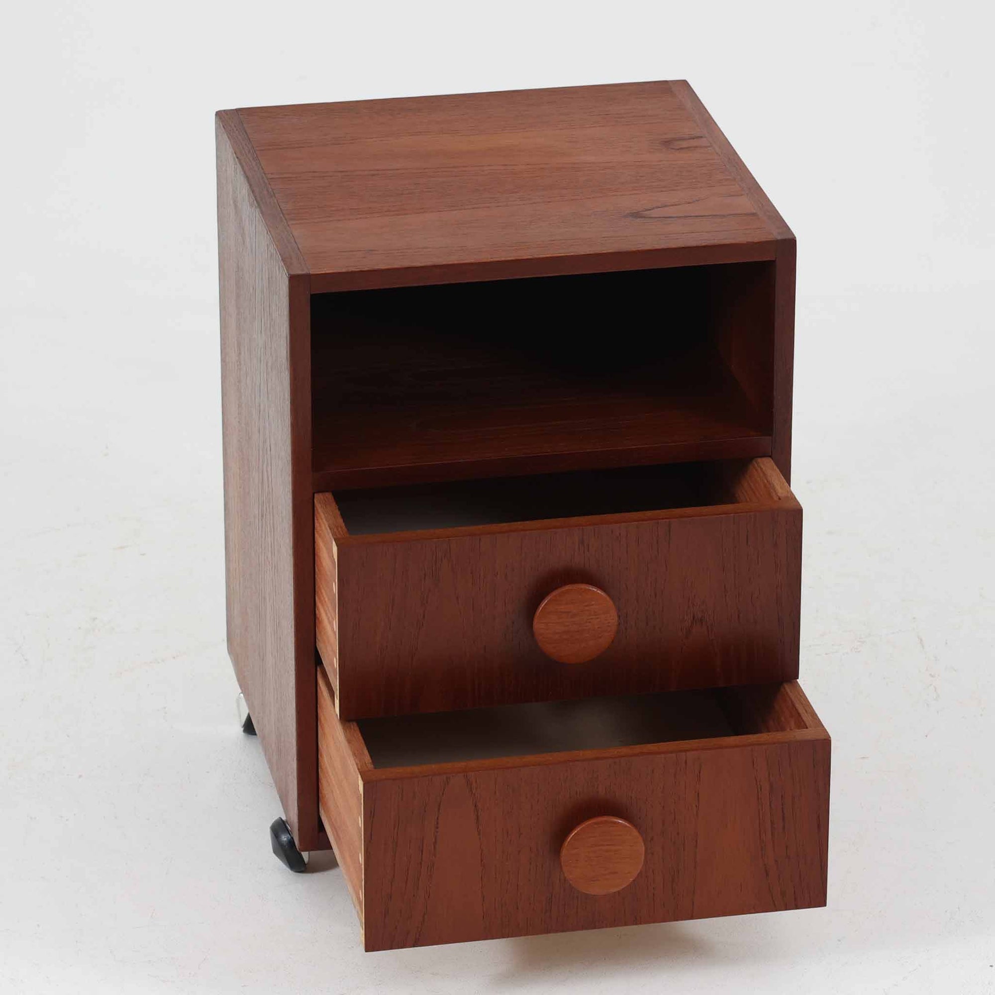 特徴的な丸型取手が目を引くこちらのサイドテーブルは、温かみのあるチーク材とシンプルな構造美が調和した北欧ビンテージ家具です。オープンスペースと2杯の引き出しに加え、英国製「ORBIT」キャスターを備え、滑らかな移動が可能です。幅40cmとコンパクトながらも機能性に優れており、ベッドサイドやソファ横の収納兼テーブルとして幅広く活躍します。実用性と遊び心を兼ね備えた一点物として、空間に心地よいアクセントを加えてくれます。