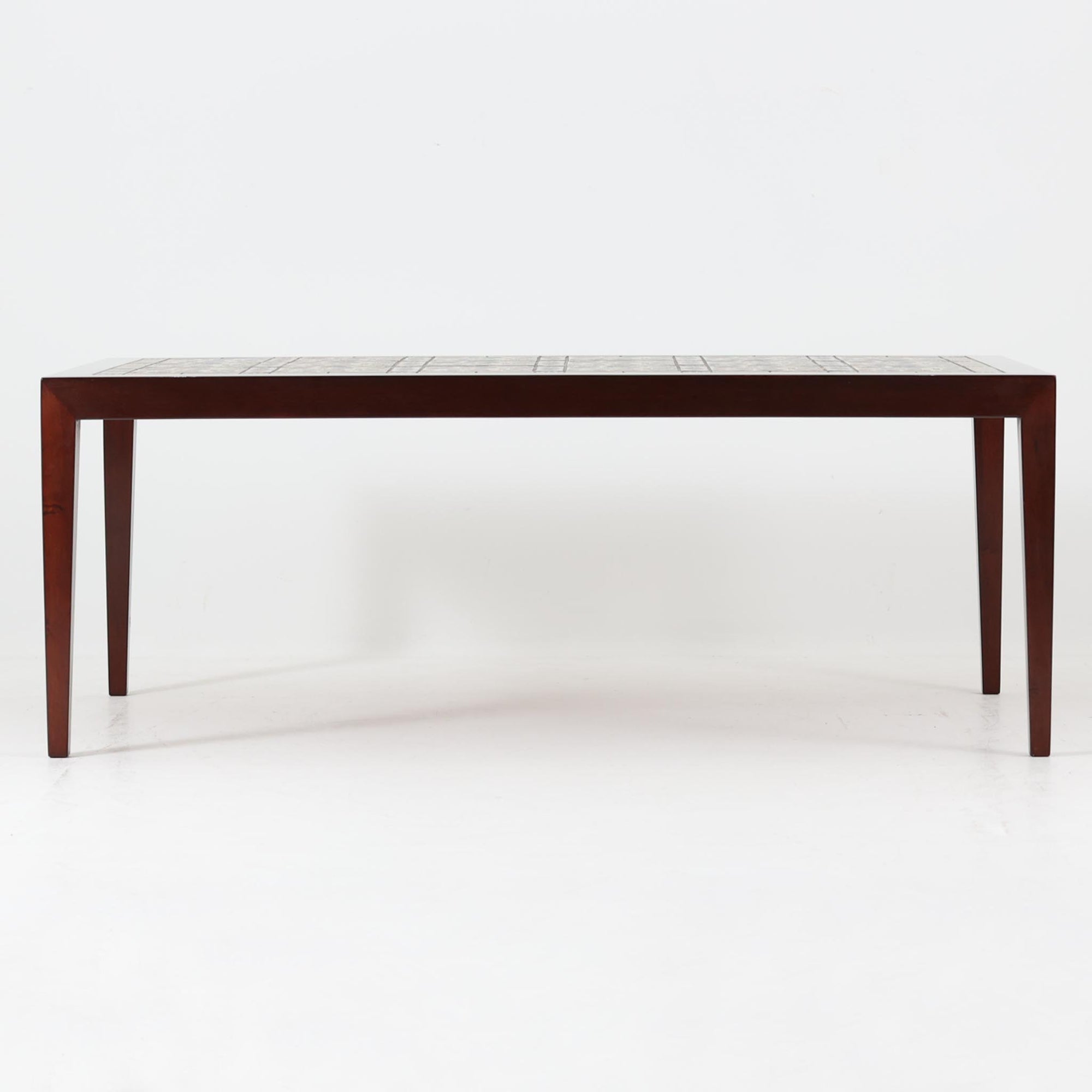 Severin Hansen Jr.によってデザインされ、Haslev社から製造されたセンターテーブルは、マホガニー材のフレームにロイヤルコペンハーゲン製Bacaシリーズのタイルをあしらった上質な一台です。精緻なカットが施された脚部と幾何学的なタイル装飾が調和し、クラフトマンシップと芸術性を兼ね備えた北欧ビンテージらしい佇まいを見せています。幅133cmのサイズ感はリビングの主役として十分な存在感を放ち、コーヒーテーブルとしてはもちろん、装飾台としてもおすすめです。