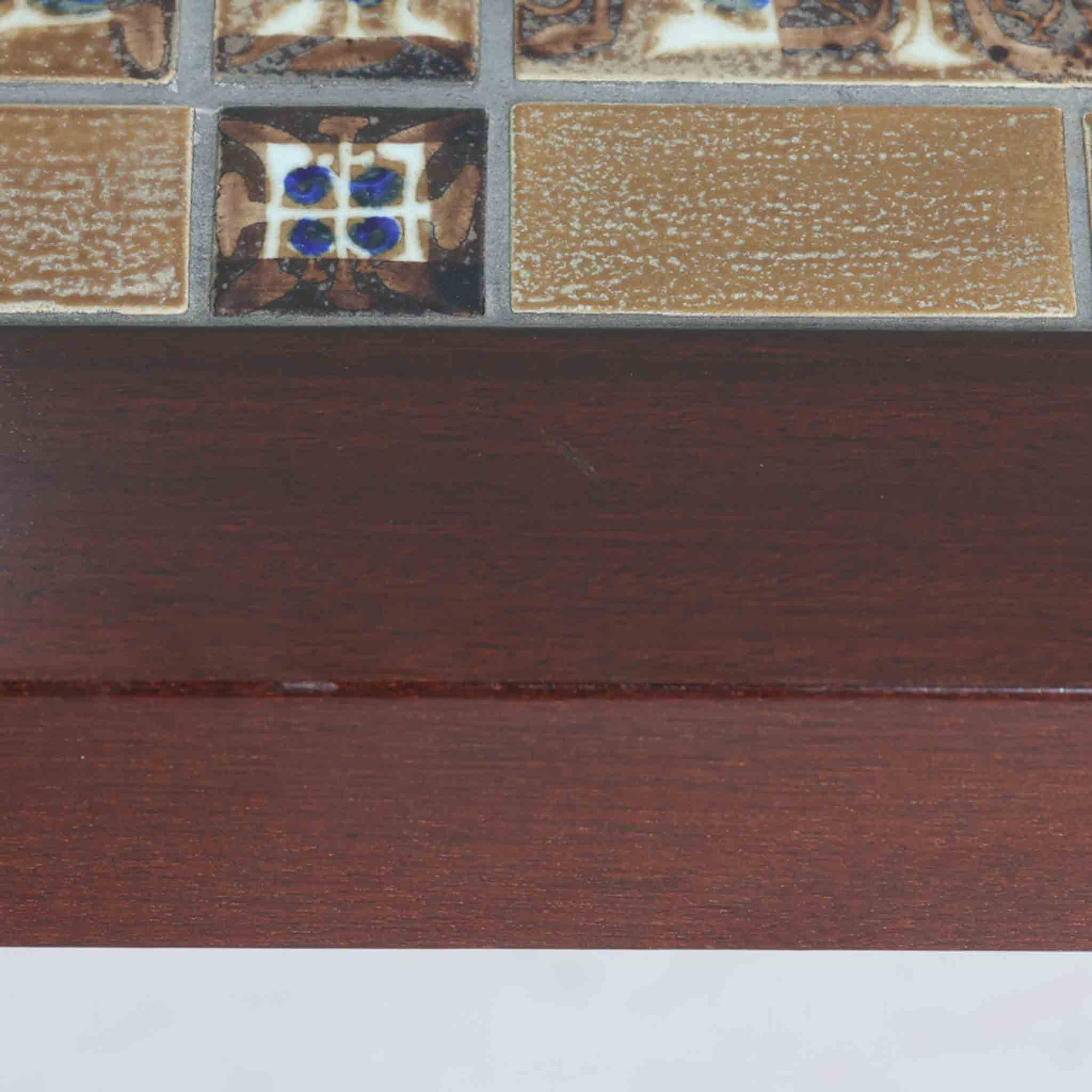 Severin Hansen Jr.によってデザインされ、Haslev社から製造されたセンターテーブルは、マホガニー材のフレームにロイヤルコペンハーゲン製Bacaシリーズのタイルをあしらった上質な一台です。精緻なカットが施された脚部と幾何学的なタイル装飾が調和し、クラフトマンシップと芸術性を兼ね備えた北欧ビンテージらしい佇まいを見せています。幅133cmのサイズ感はリビングの主役として十分な存在感を放ち、コーヒーテーブルとしてはもちろん、装飾台としてもおすすめです。