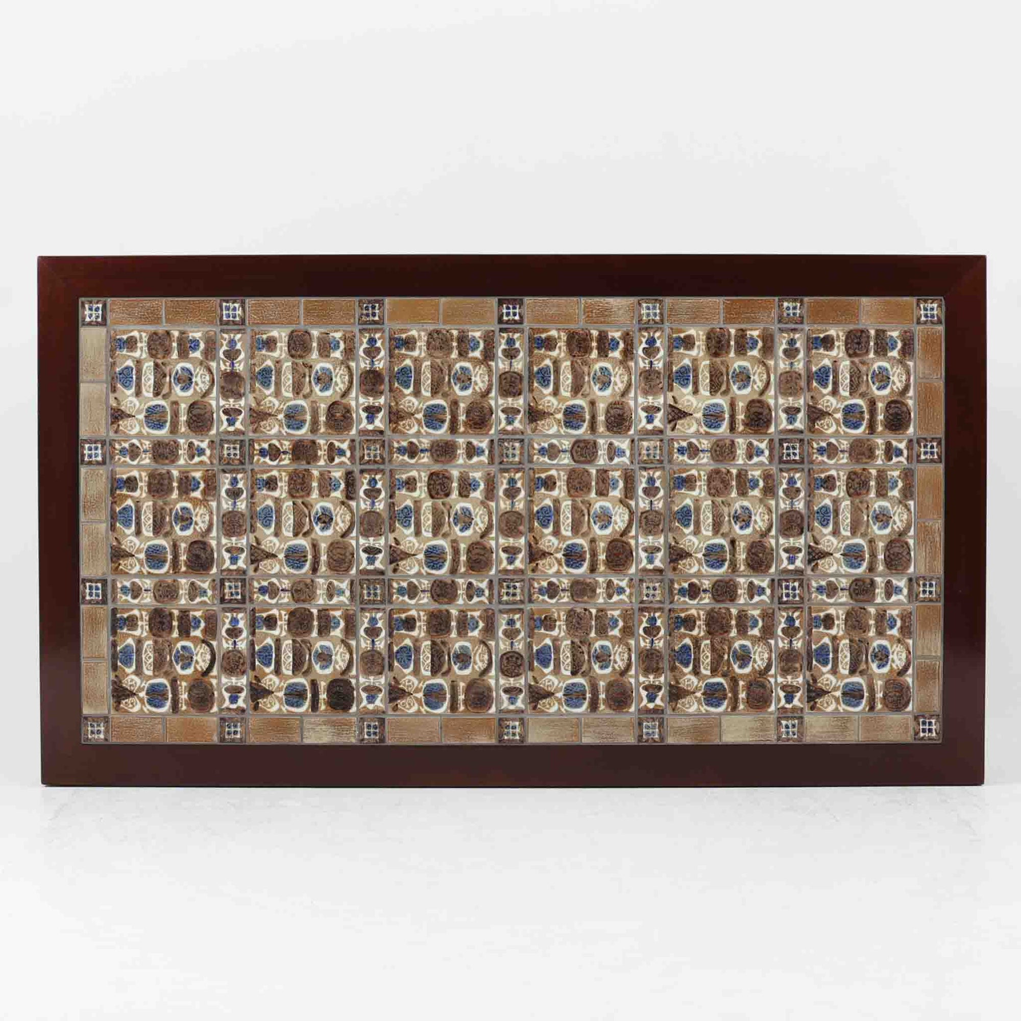 Severin Hansen Jr.によってデザインされ、Haslev社から製造されたセンターテーブルは、マホガニー材のフレームにロイヤルコペンハーゲン製Bacaシリーズのタイルをあしらった上質な一台です。精緻なカットが施された脚部と幾何学的なタイル装飾が調和し、クラフトマンシップと芸術性を兼ね備えた北欧ビンテージらしい佇まいを見せています。幅133cmのサイズ感はリビングの主役として十分な存在感を放ち、コーヒーテーブルとしてはもちろん、装飾台としてもおすすめです。