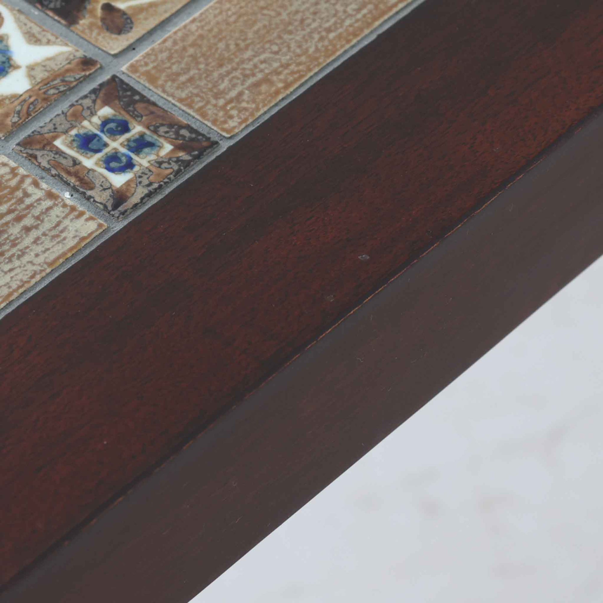 Severin Hansen Jr.によってデザインされ、Haslev社から製造されたセンターテーブルは、マホガニー材のフレームにロイヤルコペンハーゲン製Bacaシリーズのタイルをあしらった上質な一台です。精緻なカットが施された脚部と幾何学的なタイル装飾が調和し、クラフトマンシップと芸術性を兼ね備えた北欧ビンテージらしい佇まいを見せています。幅133cmのサイズ感はリビングの主役として十分な存在感を放ち、コーヒーテーブルとしてはもちろん、装飾台としてもおすすめです。