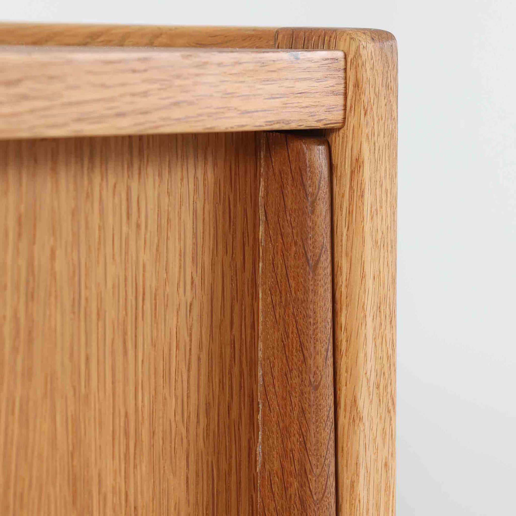 B. Fridhagenがデザインし、スウェーデンのBodafors社によって製造されたこちらのボードは、上質なオーク材を用いた小ぶりなサイズ感と、無駄を省いた洗練された意匠が魅力の一台です。スライド扉を開けると左右に仕切られた収納部が現れ、日用品や書籍の整理に最適です。細身の脚と角の立ったフレームが全体に軽やかな印象を与え、空間を圧迫せず設置できます。シンプルながらも素材の美しさと北欧らしい実用性が際立つ、希少なビンテージ家具です。