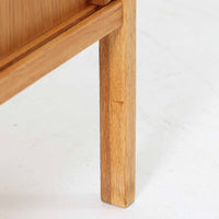 B. Fridhagenがデザインし、スウェーデンのBodafors社によって製造されたこちらのボードは、上質なオーク材を用いた小ぶりなサイズ感と、無駄を省いた洗練された意匠が魅力の一台です。スライド扉を開けると左右に仕切られた収納部が現れ、日用品や書籍の整理に最適です。細身の脚と角の立ったフレームが全体に軽やかな印象を与え、空間を圧迫せず設置できます。シンプルながらも素材の美しさと北欧らしい実用性が際立つ、希少なビンテージ家具です。