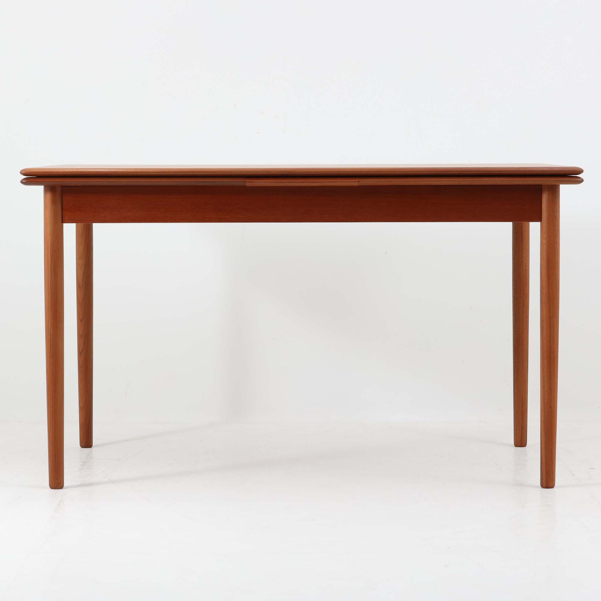 デンマーク製のエクステンションダイニングテーブルです。上質なチーク材が使用されており、木目の美しさと経年による深みのある色合いが魅力です。両サイドに拡張板を備え、幅128cmから最大231cmまで伸長可能で、シーンに応じて柔軟に対応できます。シンプルで端正なフォルムと細身の丸脚が軽やかな印象を与え、ダイニングの中心として存在感を放ちます。普段はコンパクトに、来客時にはゆったりと使える実用性に優れたビンテージ家具です。