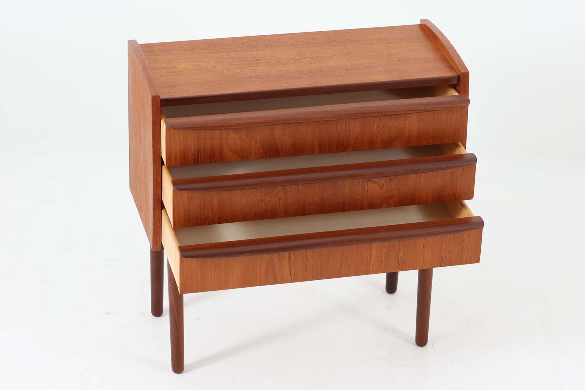 特徴的な丸みを帯びた側板と、典型的なデンマーク家具らしいバータイプの取手が素敵なデザインです。また、天板の両側面は物が落ちにくいように出っ張っており、実用性も考慮されています。本体には上質なチーク材が使用されています。使い勝手の良い小ぶりなサイズ感です。