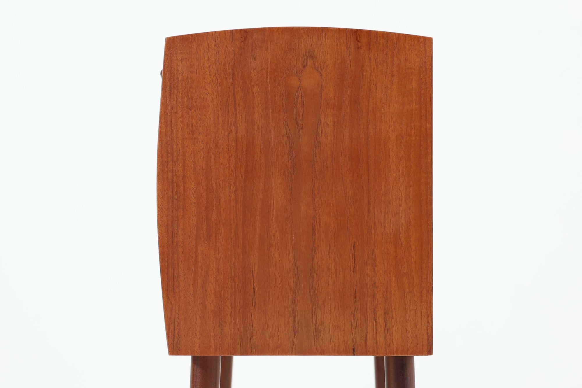 特徴的な丸みを帯びた側板と、典型的なデンマーク家具らしいバータイプの取手が素敵なデザインです。また、天板の両側面は物が落ちにくいように出っ張っており、実用性も考慮されています。本体には上質なチーク材が使用されています。使い勝手の良い小ぶりなサイズ感です。