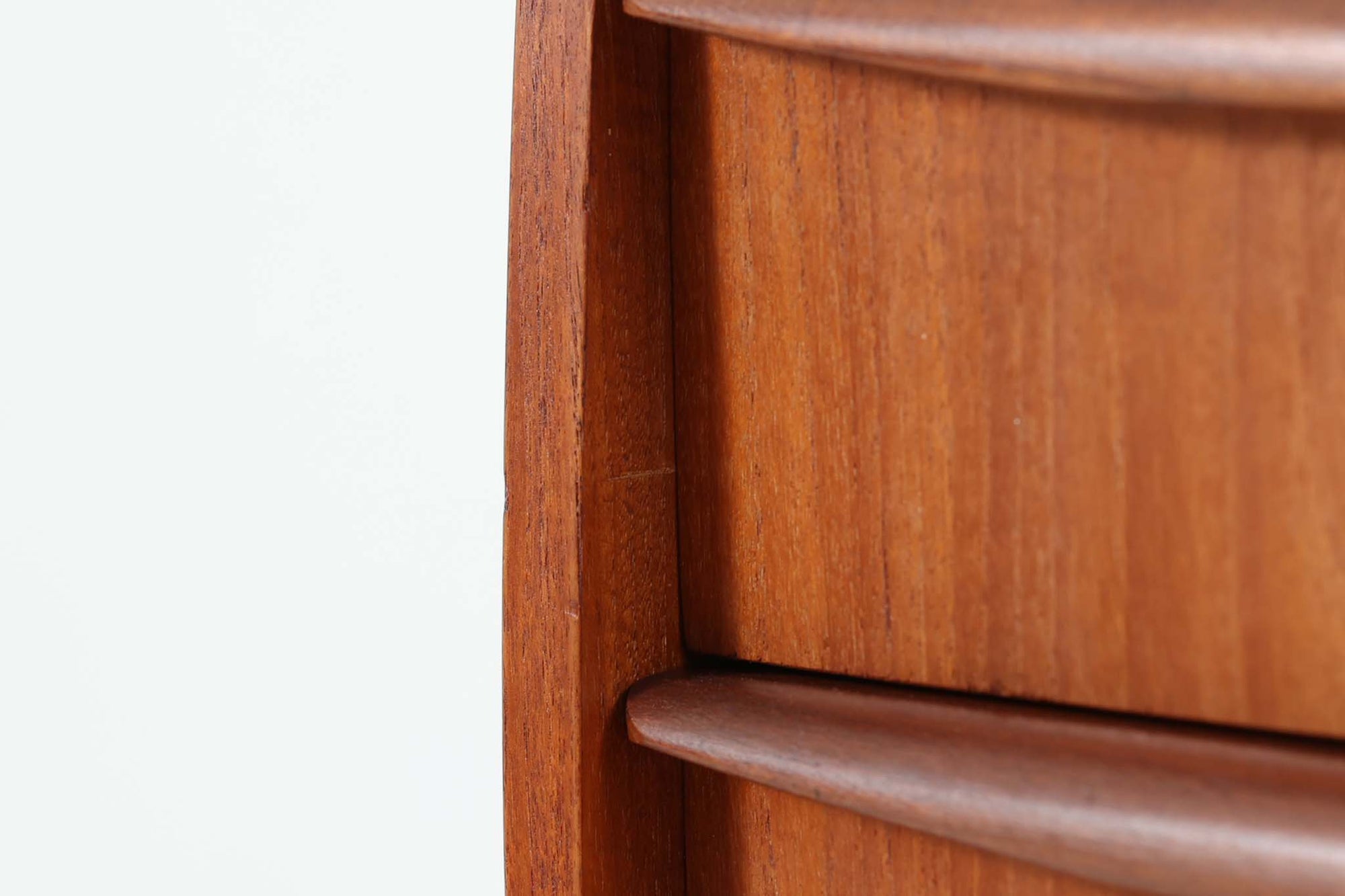 特徴的な丸みを帯びた側板と、典型的なデンマーク家具らしいバータイプの取手が素敵なデザインです。また、天板の両側面は物が落ちにくいように出っ張っており、実用性も考慮されています。本体には上質なチーク材が使用されています。使い勝手の良い小ぶりなサイズ感です。