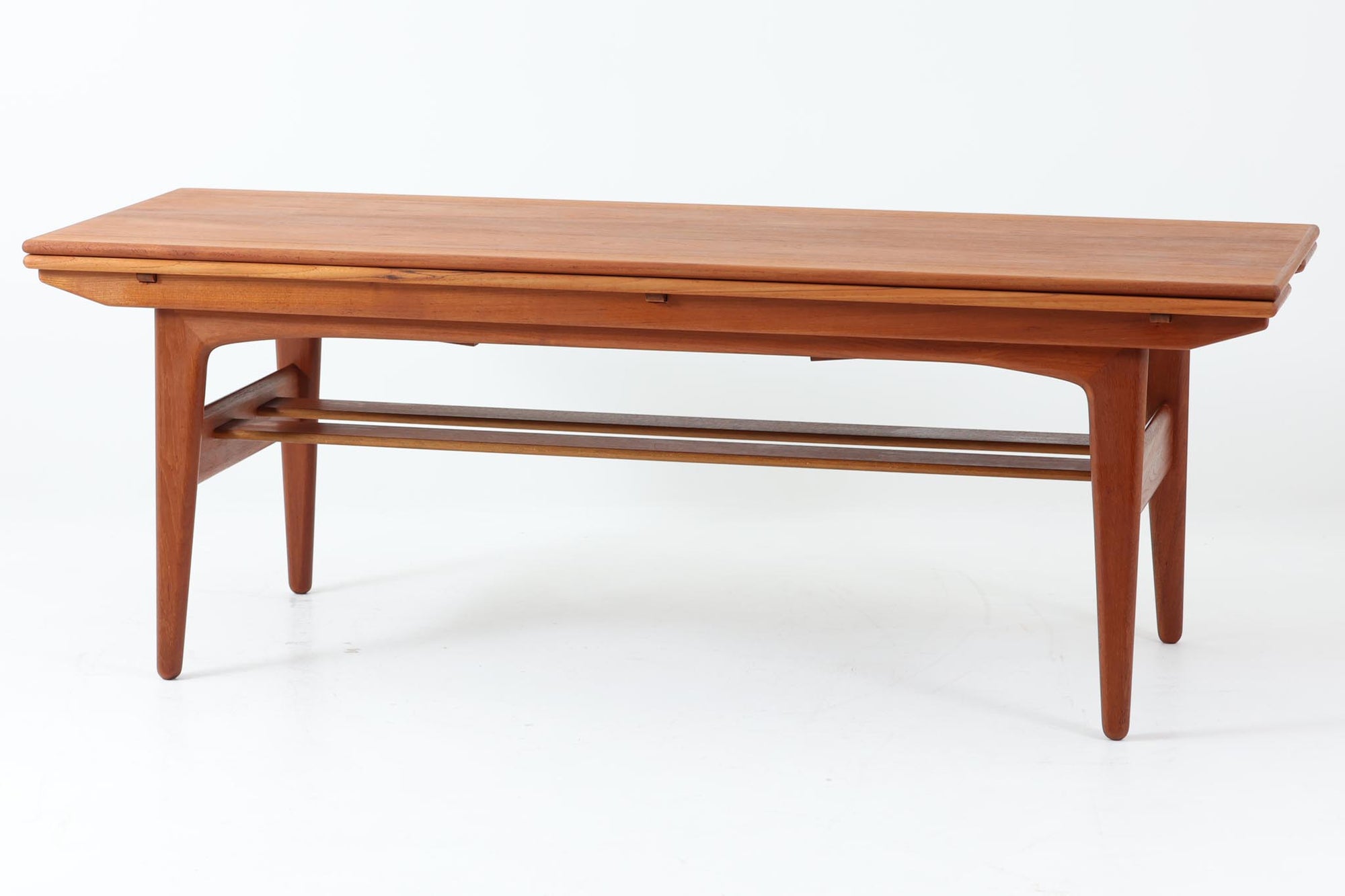 Kai Kristiansenデザインのエレベーターテーブルは、デンマークの名工Trioh moblerによって手作りされたシンプルで滑らかなデザインの逸品です。このテーブルは環境に応じて大きさを変えることができるため、デンマークではスタンダードアイテムとなっています。天板を片側だけ広げたり、高さを調整したりと、非常に機能的です。こちらは天板下に棚がある珍しいタイプです。1960年代にデザインされたものですが、丁寧にメンテナンスを行っているため長くお使いいただけます。