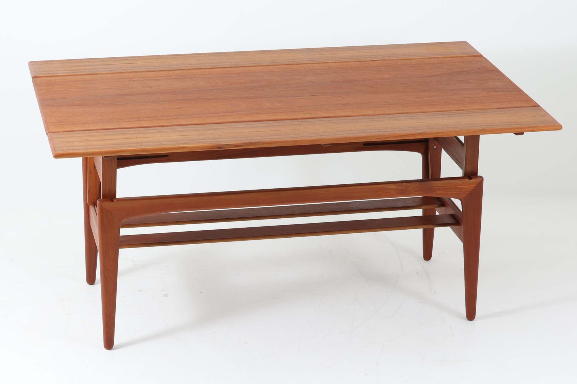 Kai Kristiansenデザインのエレベーターテーブルは、デンマークの名工Trioh moblerによって手作りされたシンプルで滑らかなデザインの逸品です。このテーブルは環境に応じて大きさを変えることができるため、デンマークではスタンダードアイテムとなっています。天板を片側だけ広げたり、高さを調整したりと、非常に機能的です。こちらは天板下に棚がある珍しいタイプです。1960年代にデザインされたものですが、丁寧にメンテナンスを行っているため長くお使いいただけます。