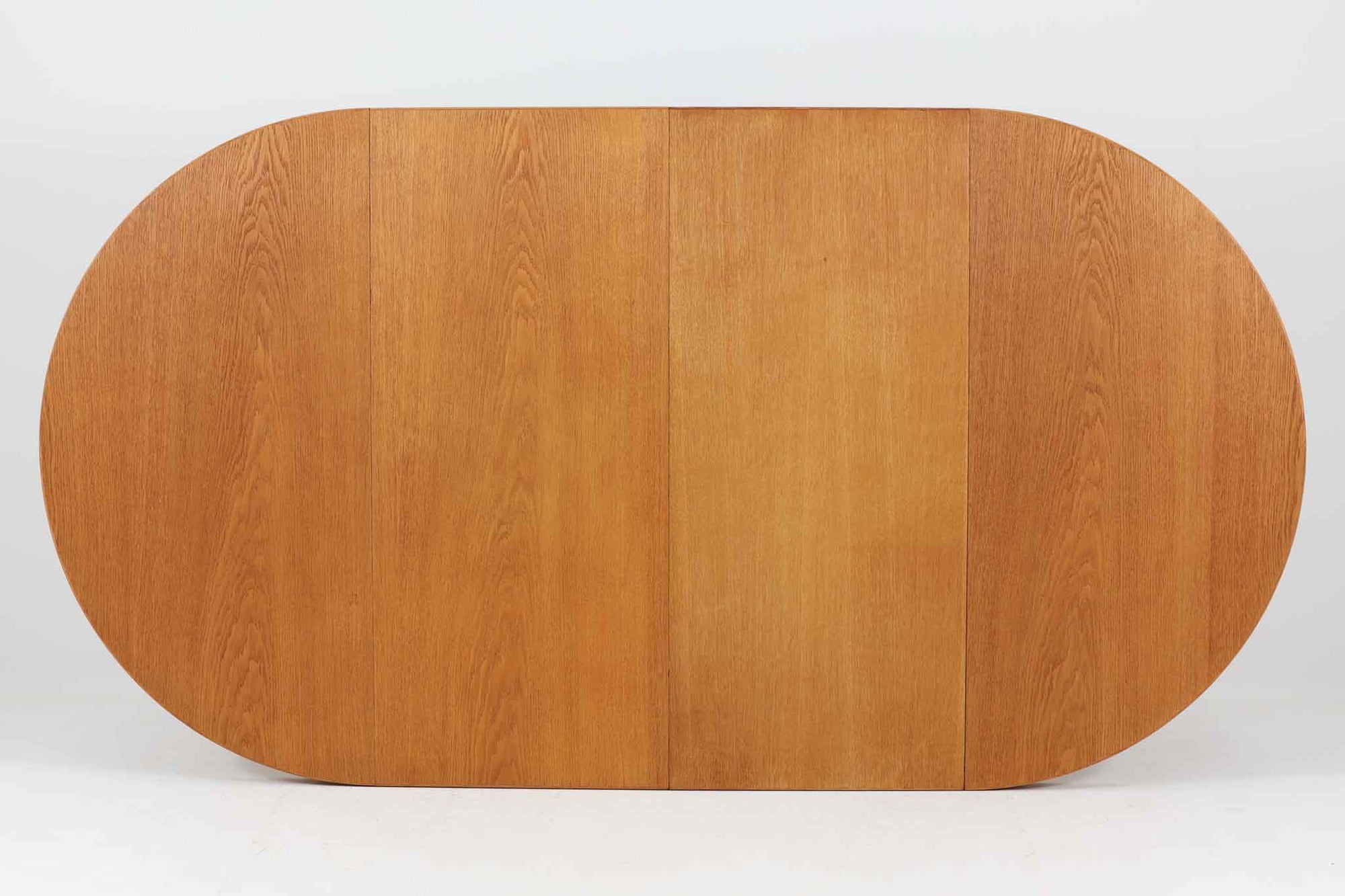 美しい木目のオーク材で作られたデンマーク製のビンテージダイニングテーブルです。シンプルでありながら北欧らしい洗練されたデザインが魅力で、エクステンション機能により天板を伸長して大人数にも対応可能です。天板を閉じた状態では直径のある円形テーブルとして、拡張時には楕円形になり広々とご使用いただけます。丸みを帯びた天板のエッジと先細りの脚が軽やかで、どんな空間にも調和します。Danish Controlの刻印も確認でき、品質の高さが伺える逸品です。北欧モダンな空間演出におすすめの一台です。