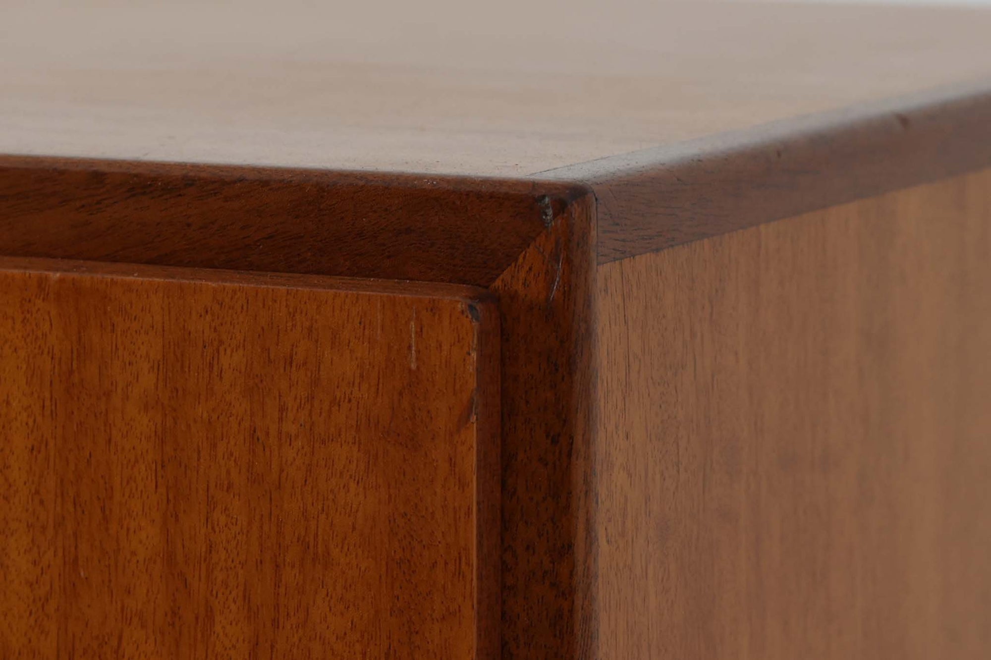 FDBモブラーでBorge mogensenの後任としてアートディレクターを務めたPoul m. Voltherによる、美しく洗練されたキャビネット。良質なマホガニー材の本体に、ビーチ材の脚部を組み合わせたコントラストが魅力です。真鍮の丸い鍵穴が特徴的な3枚の扉を備え、中央には調節可能な棚、両側には精巧な蟻継ぎが施された移動式の引き出しを配しています。下部には真鍮の俵型ハンドル付きの引き出しが3杯並び、細部へのこだわりが際立ちます。また、室内で靴を履く文化に配慮し、脚先には汚れ防止のための濃い塗装が施されています。1950年代にデザインされた本作は、先細りの脚やストレッチャーがミニマルな美しさを際立たせる一方、シンメトリーなフォルムや真鍮の装飾が伝統的なエレガンスを醸し出し、モダンとクラシックが調和した逸品です。