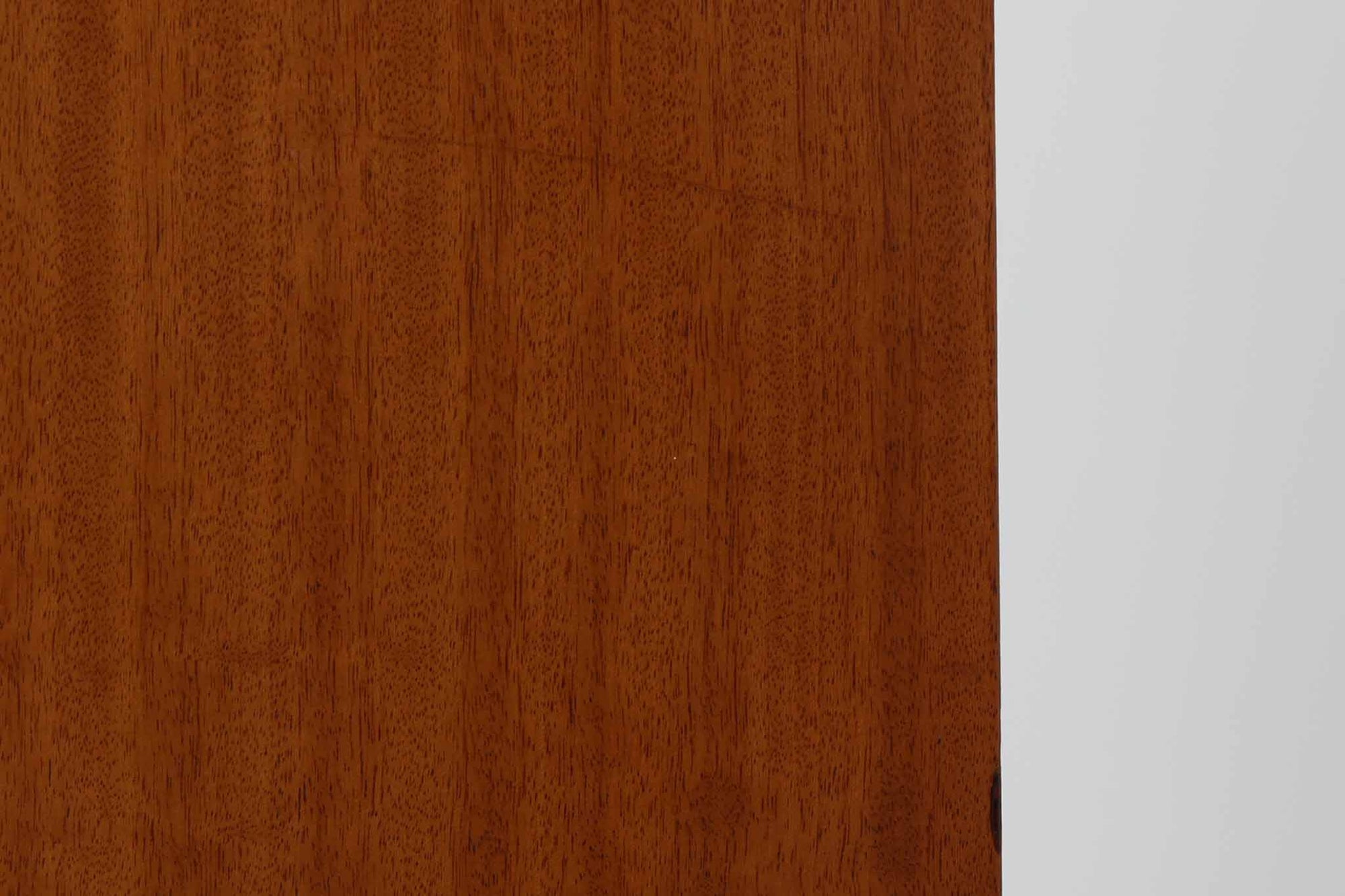 FDBモブラーでBorge mogensenの後任としてアートディレクターを務めたPoul m. Voltherによる、美しく洗練されたキャビネット。良質なマホガニー材の本体に、ビーチ材の脚部を組み合わせたコントラストが魅力です。真鍮の丸い鍵穴が特徴的な3枚の扉を備え、中央には調節可能な棚、両側には精巧な蟻継ぎが施された移動式の引き出しを配しています。下部には真鍮の俵型ハンドル付きの引き出しが3杯並び、細部へのこだわりが際立ちます。また、室内で靴を履く文化に配慮し、脚先には汚れ防止のための濃い塗装が施されています。1950年代にデザインされた本作は、先細りの脚やストレッチャーがミニマルな美しさを際立たせる一方、シンメトリーなフォルムや真鍮の装飾が伝統的なエレガンスを醸し出し、モダンとクラシックが調和した逸品です。