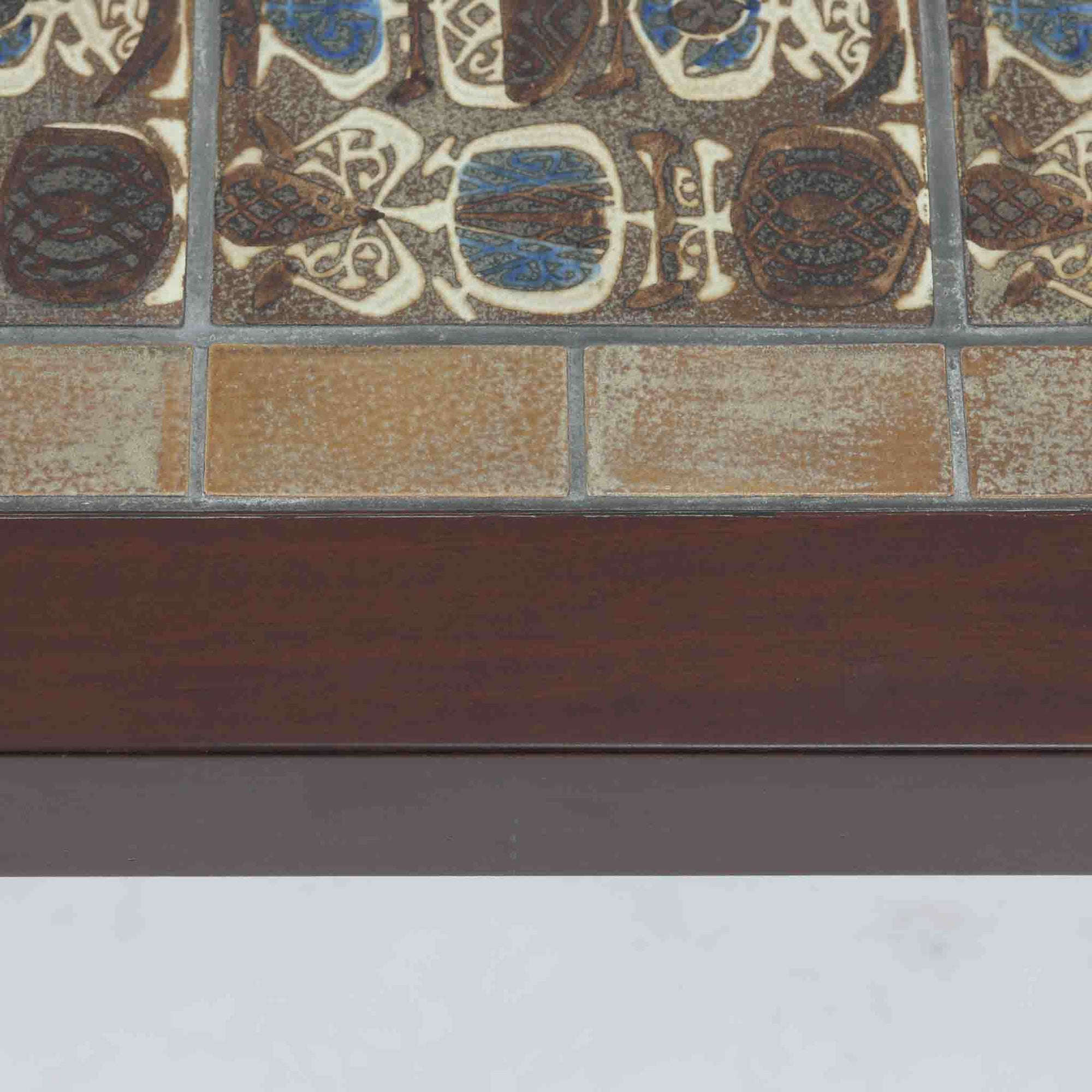 Nils Thorssonがデザインを手掛け、Royal CopenhagenのBACAシリーズのタイルを天板に配したセンターテーブルです。家具メーカーHaslev社により製作され、マホガニー材の落ち着いた木目と、幾何学的で温かみのあるタイル意匠が美しく調和しています。直線的で端正なフォルムは空間をすっきりと見せ、リビングの主役としてはもちろん、ソファ前のローテーブルとしても活躍。経年により深みを増した木部と味わい豊かな陶板が、北欧ビンテージならではの存在感を放つ一品です。