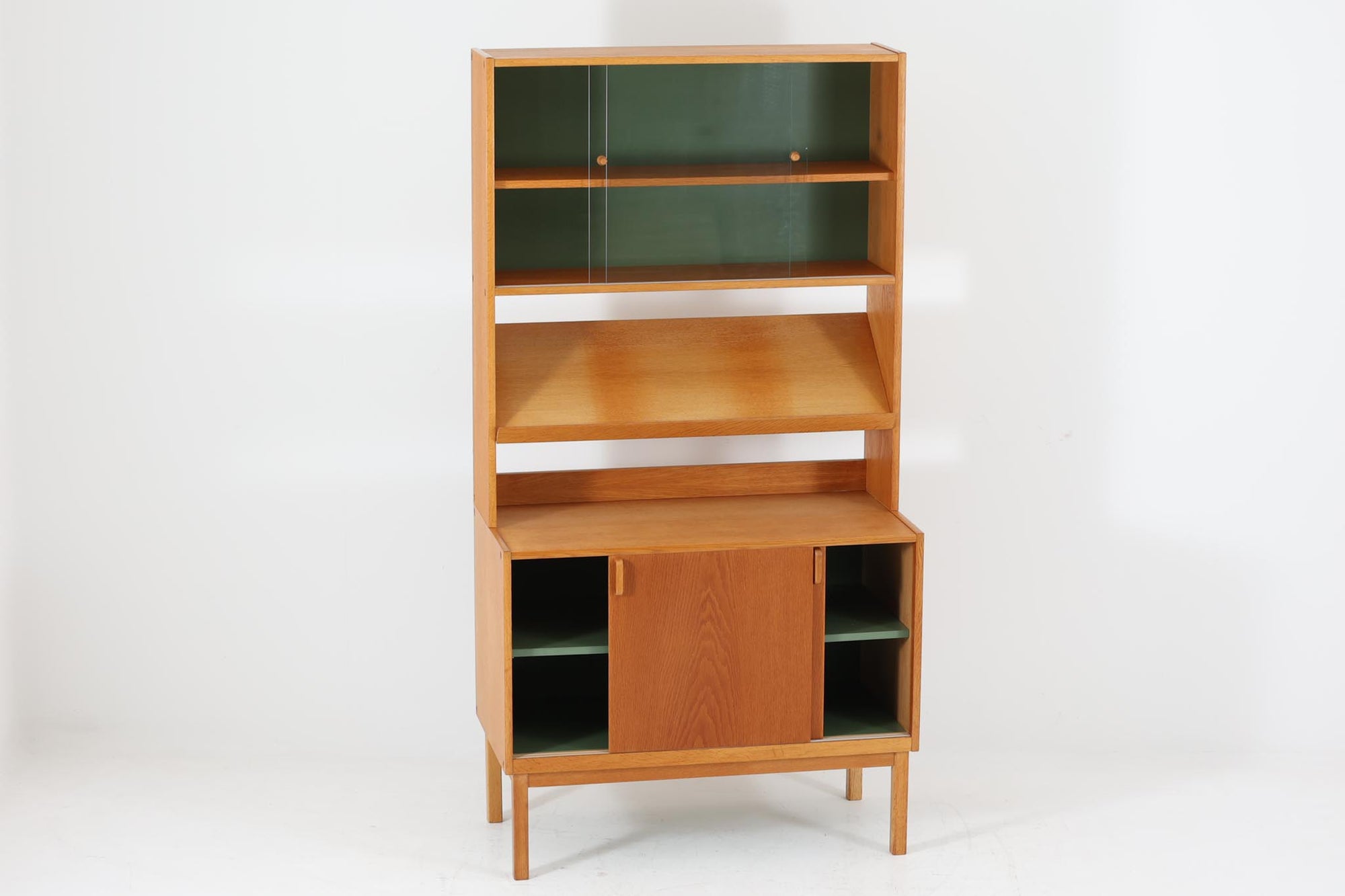 スウェーデンより買い付けました。デザインのポイントはガラス戸で、中央部の棚板は本が置けるように傾斜がついています。チーク材とオーク材の組み合わせが美しく、背面のモスグリーンが差し色となっています。