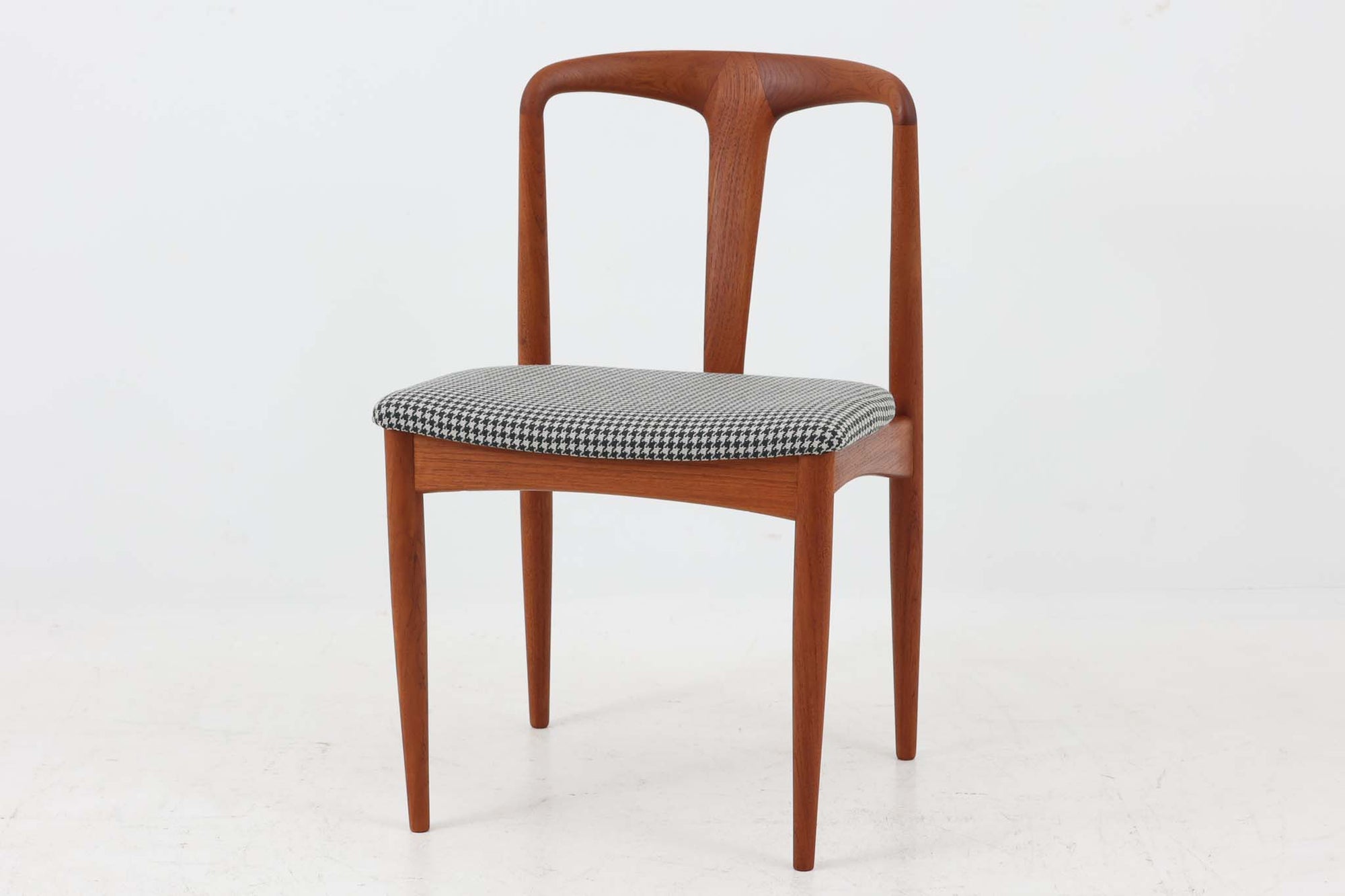 Johannes Andersenデザインの「Julian Chair」は、1960年代にUldum mobelfabrik社から発表されたチーク材のダイニングチェアです。特徴的な美しい曲線を描く背もたれと広めに設計された座面は、背中をしっかりと支え、快適な座り心地を提供します。彫刻的な軽快なフレームと実用性を兼ね備えたデザインが魅力的で、チーク材の温かみのある色味を引き立てています。