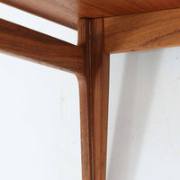 デンマークの巨匠フィン・ユールによるデザイン、France & Son社製のサイドテーブル「FD635」です。ロゴより1957年頃に製造されたと推測される本品は、チーク無垢材を贅沢に使用し、滑らかな脚部の曲線と柔らかなエッジラインが見事に調和した美しいデザインが魅力です。天板の縁にはわずかな立ち上がりが設けられ、機能性と造形美を兼ね備えた構造となっています。彫刻的ともいえる有機的なフォルムはフィン・ユールの真骨頂であり、リビングやベッドサイドで北欧家具の上質な存在感を引き立てる逸品です。