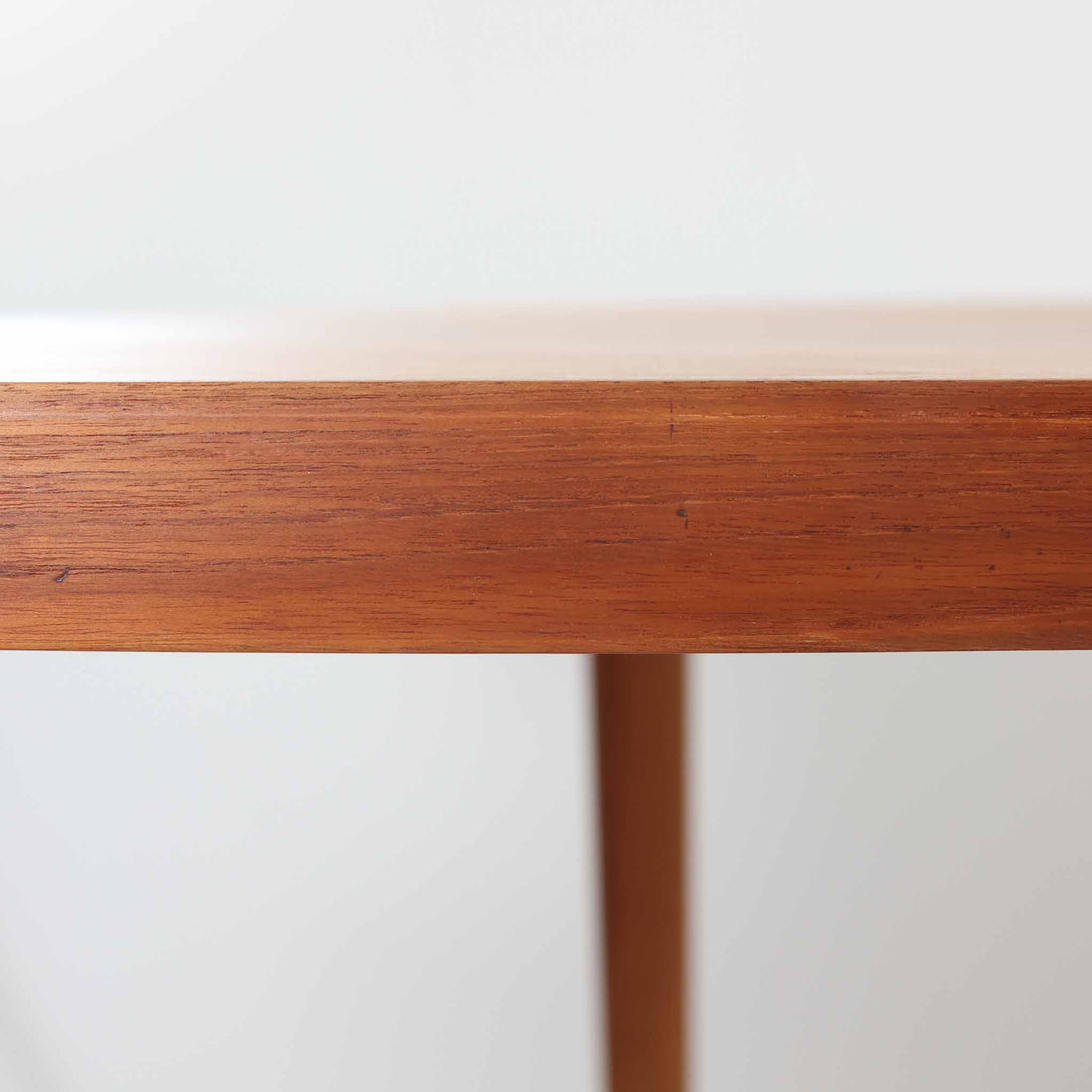 デンマーク製円形エクステンションダイニングテーブルです。チーク材特有の温かみある木目が美しく、滑らかな質感が空間に上質な印象を与えます。幕板と天板が一体化した構造により、すっきりとした見た目と安定感のある構造を両立。天板中央の拡張板を取り付けることで人数や用途に合わせてサイズを調整でき、普段使いから来客時まで幅広く対応します。テーパー脚が軽やかな印象を添え、経年で深みを増したチークの色合いが北欧ビンテージならではの魅力を引き立てます。