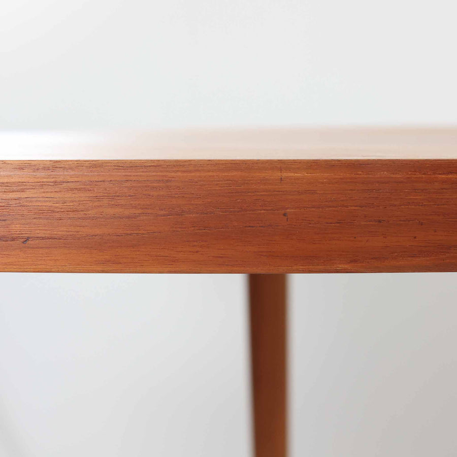 デンマーク製円形エクステンションダイニングテーブルです。チーク材特有の温かみある木目が美しく、滑らかな質感が空間に上質な印象を与えます。幕板と天板が一体化した構造により、すっきりとした見た目と安定感のある構造を両立。天板中央の拡張板を取り付けることで人数や用途に合わせてサイズを調整でき、普段使いから来客時まで幅広く対応します。テーパー脚が軽やかな印象を添え、経年で深みを増したチークの色合いが北欧ビンテージならではの魅力を引き立てます。