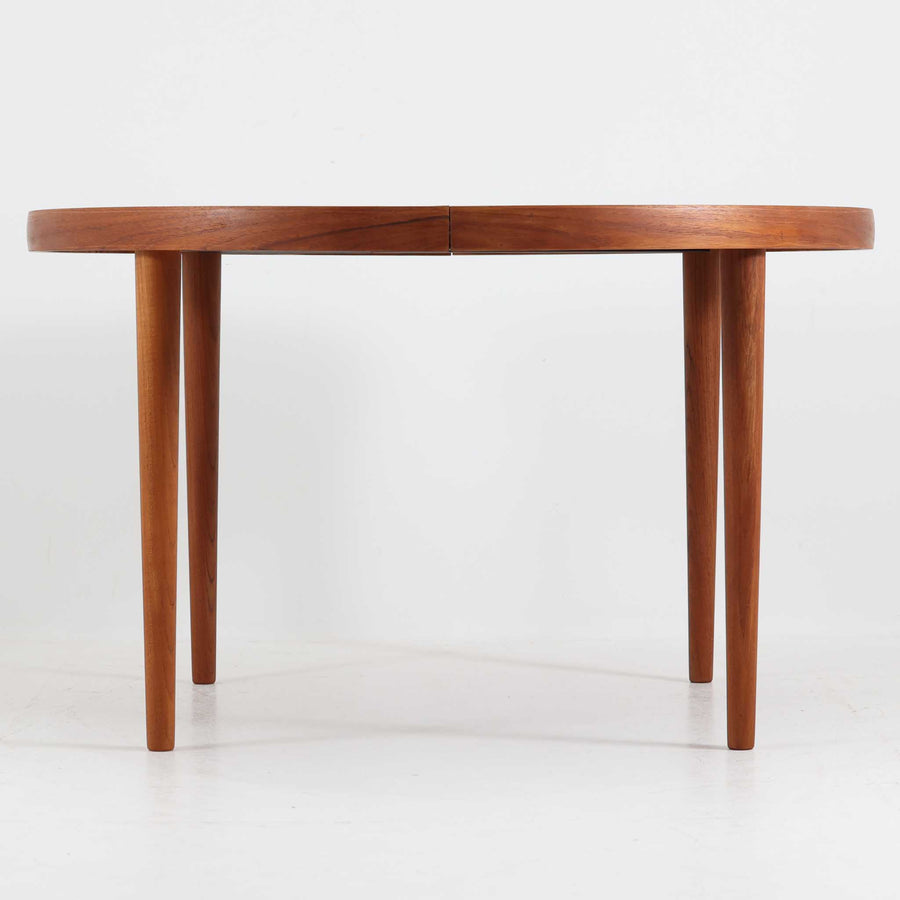 デンマーク製円形エクステンションダイニングテーブルです。チーク材特有の温かみある木目が美しく、滑らかな質感が空間に上質な印象を与えます。幕板と天板が一体化した構造により、すっきりとした見た目と安定感のある構造を両立。天板中央の拡張板を取り付けることで人数や用途に合わせてサイズを調整でき、普段使いから来客時まで幅広く対応します。テーパー脚が軽やかな印象を添え、経年で深みを増したチークの色合いが北欧ビンテージならではの魅力を引き立てます。