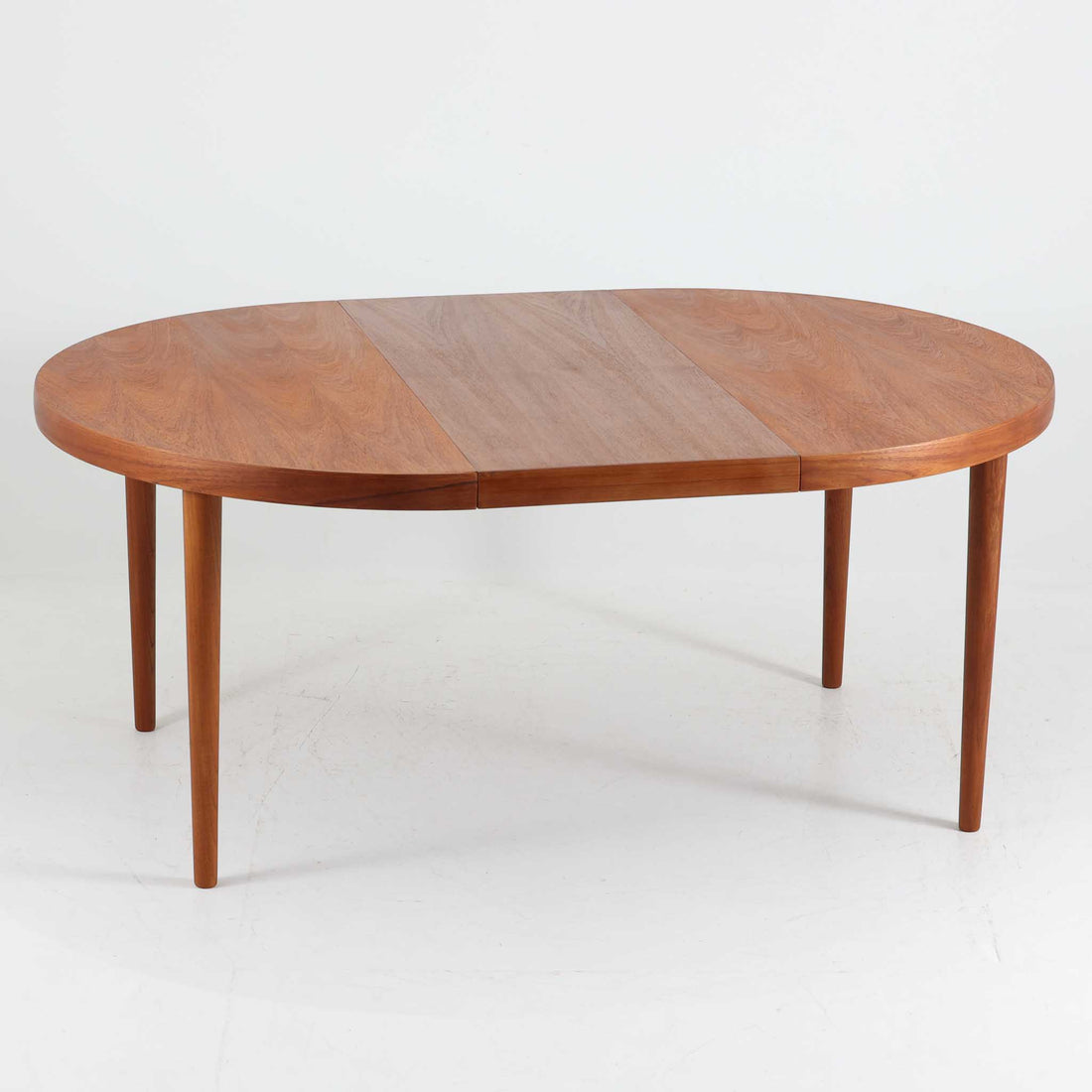 デンマーク製円形エクステンションダイニングテーブルです。チーク材特有の温かみある木目が美しく、滑らかな質感が空間に上質な印象を与えます。幕板と天板が一体化した構造により、すっきりとした見た目と安定感のある構造を両立。天板中央の拡張板を取り付けることで人数や用途に合わせてサイズを調整でき、普段使いから来客時まで幅広く対応します。テーパー脚が軽やかな印象を添え、経年で深みを増したチークの色合いが北欧ビンテージならではの魅力を引き立てます。