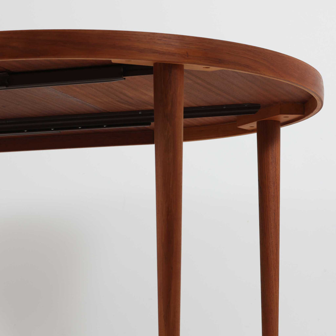 デンマーク製円形エクステンションダイニングテーブルです。チーク材特有の温かみある木目が美しく、滑らかな質感が空間に上質な印象を与えます。幕板と天板が一体化した構造により、すっきりとした見た目と安定感のある構造を両立。天板中央の拡張板を取り付けることで人数や用途に合わせてサイズを調整でき、普段使いから来客時まで幅広く対応します。テーパー脚が軽やかな印象を添え、経年で深みを増したチークの色合いが北欧ビンテージならではの魅力を引き立てます。