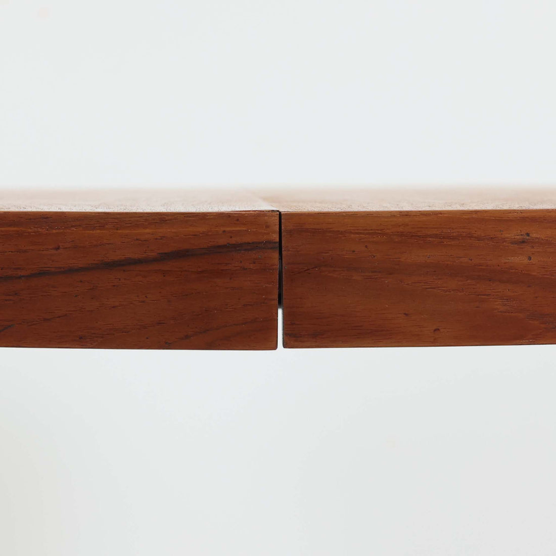 デンマーク製円形エクステンションダイニングテーブルです。チーク材特有の温かみある木目が美しく、滑らかな質感が空間に上質な印象を与えます。幕板と天板が一体化した構造により、すっきりとした見た目と安定感のある構造を両立。天板中央の拡張板を取り付けることで人数や用途に合わせてサイズを調整でき、普段使いから来客時まで幅広く対応します。テーパー脚が軽やかな印象を添え、経年で深みを増したチークの色合いが北欧ビンテージならではの魅力を引き立てます。