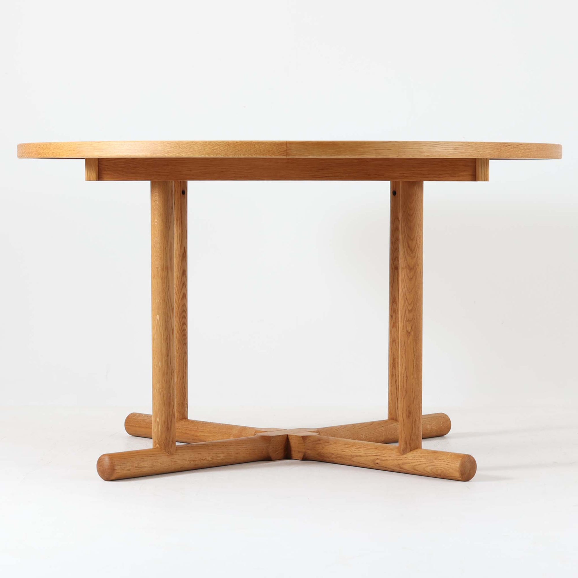 デンマークのデザイナー、Kurt Ostervig（カート・ウストヴィ）が手がけ、Jason Mobler社から発表された円形エクステンションダイニングテーブル。美しいオーク材の木目と、円形から楕円形へと広がる機能性を兼ね備えた一台です。交差する脚部の構造が彫刻的な存在感を放ち、視覚的な安定感も演出します。中央のリーフを追加することで来客時にも対応でき、実用性とデザイン性を両立。経年によるオーク材の味わい深い表情と丁寧な仕上げが、北欧ビンテージ家具ならではの魅力を感じさせます。ダイニングだけでなく、作業台としての使用にもおすすめです。