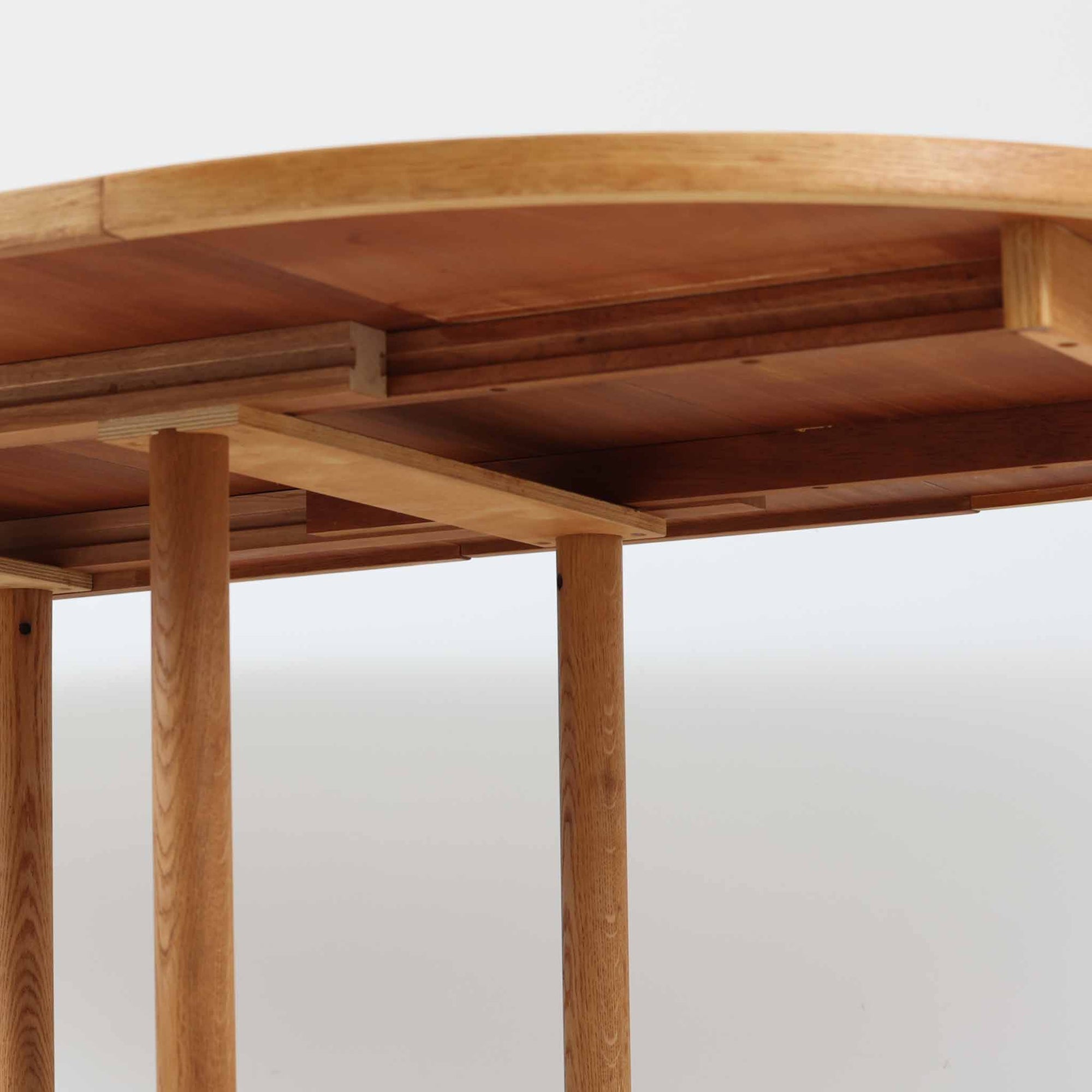 デンマークのデザイナー、Kurt Ostervig（カート・ウストヴィ）が手がけ、Jason Mobler社から発表された円形エクステンションダイニングテーブル。美しいオーク材の木目と、円形から楕円形へと広がる機能性を兼ね備えた一台です。交差する脚部の構造が彫刻的な存在感を放ち、視覚的な安定感も演出します。中央のリーフを追加することで来客時にも対応でき、実用性とデザイン性を両立。経年によるオーク材の味わい深い表情と丁寧な仕上げが、北欧ビンテージ家具ならではの魅力を感じさせます。ダイニングだけでなく、作業台としての使用にもおすすめです。